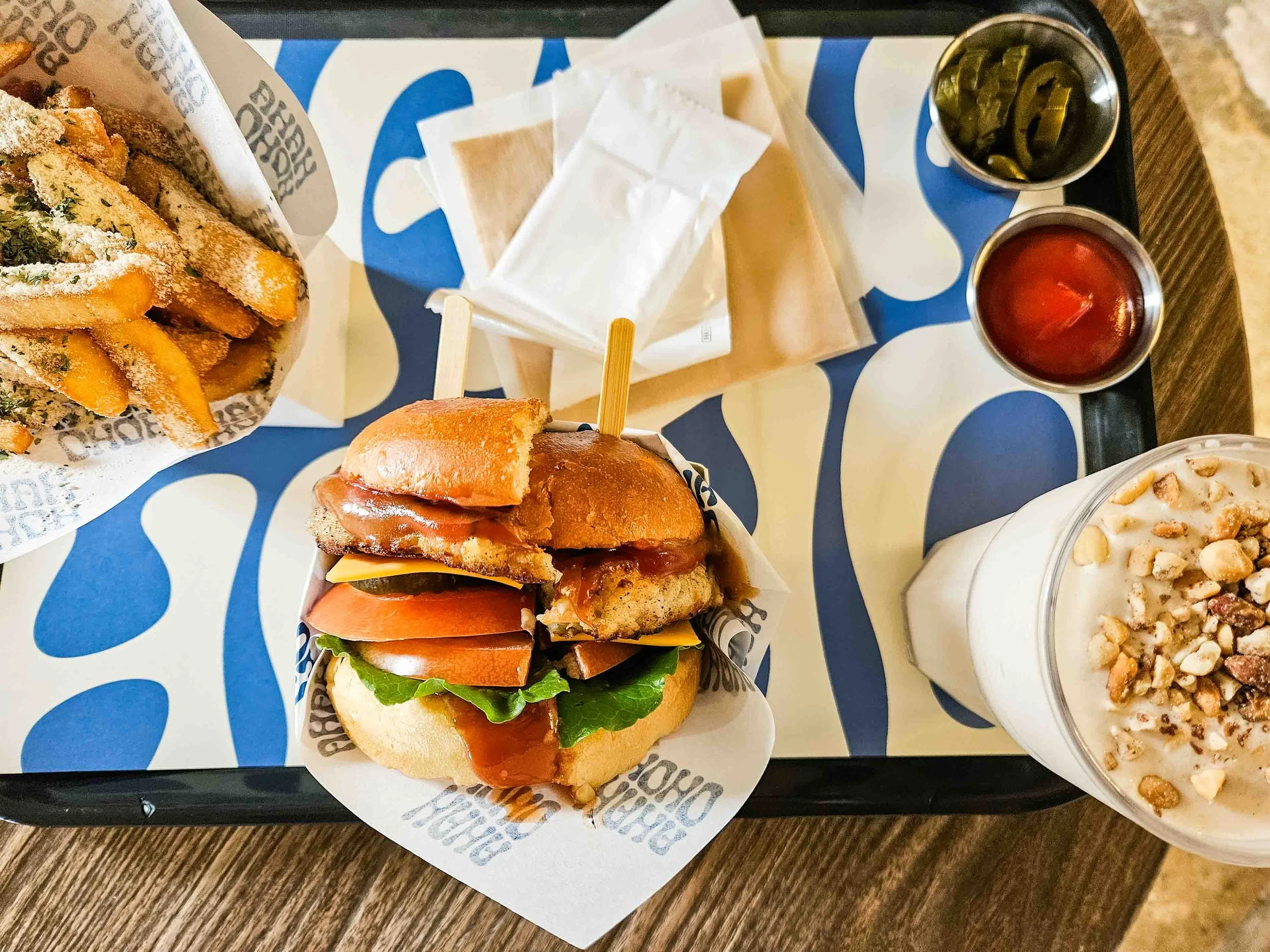 Shrimp burger with french fries and a peanut shake on a tray served inside the HAHA HOHO Cafe on Udo island.