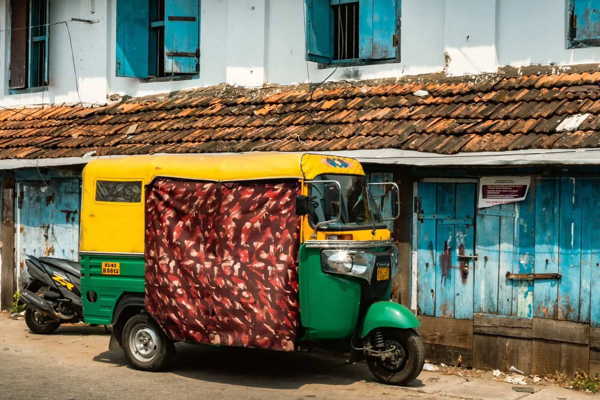 A yellow tuktuk in front of colonial building in Fort Kochi, Kerala.