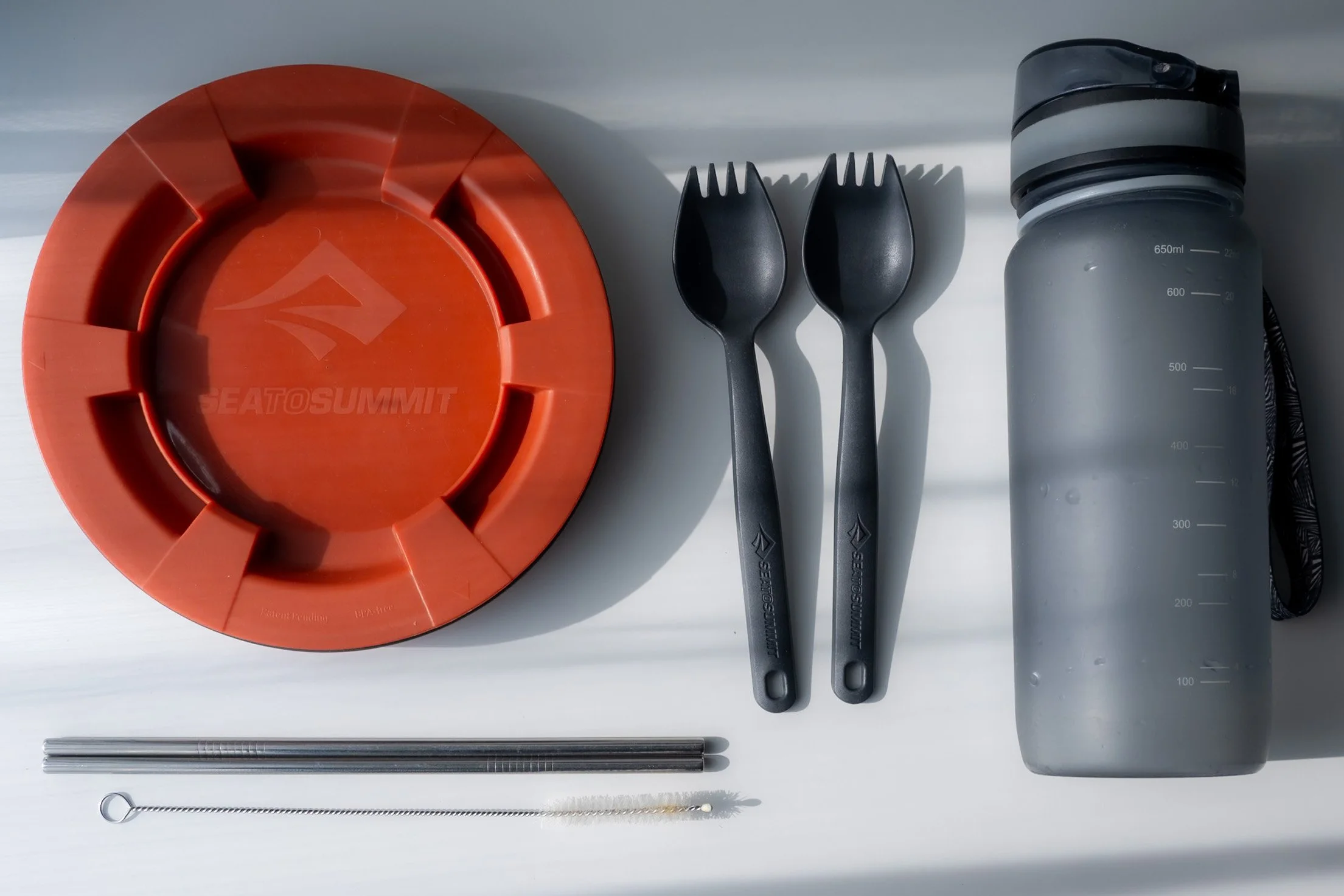 Sustainable food and drink staples like a reusable food container and drinkng bottle for traveling.