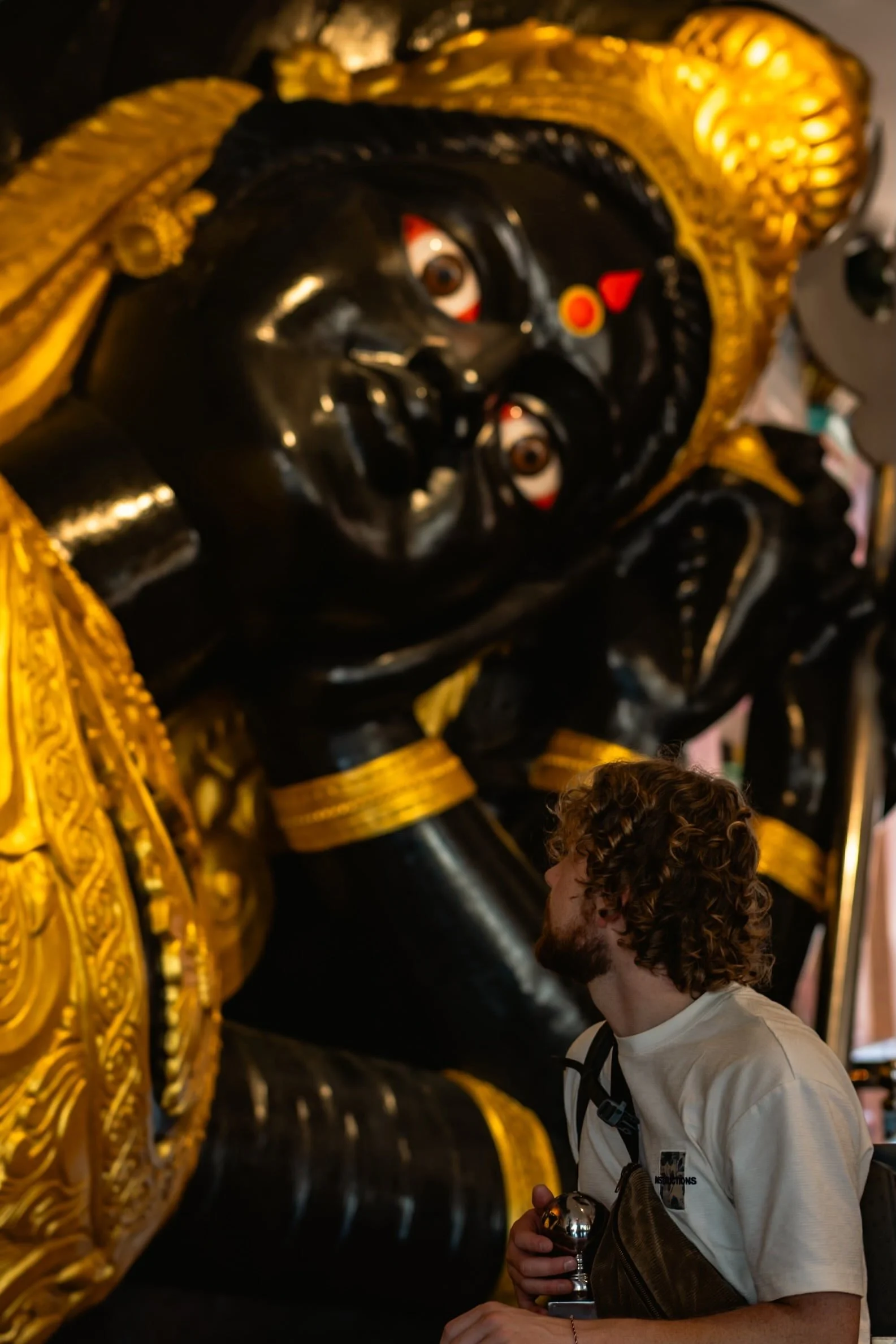 A traveler inside the temples of Batu Caves, admiring a huge & magnificent idol of a Hindu deity in the background.