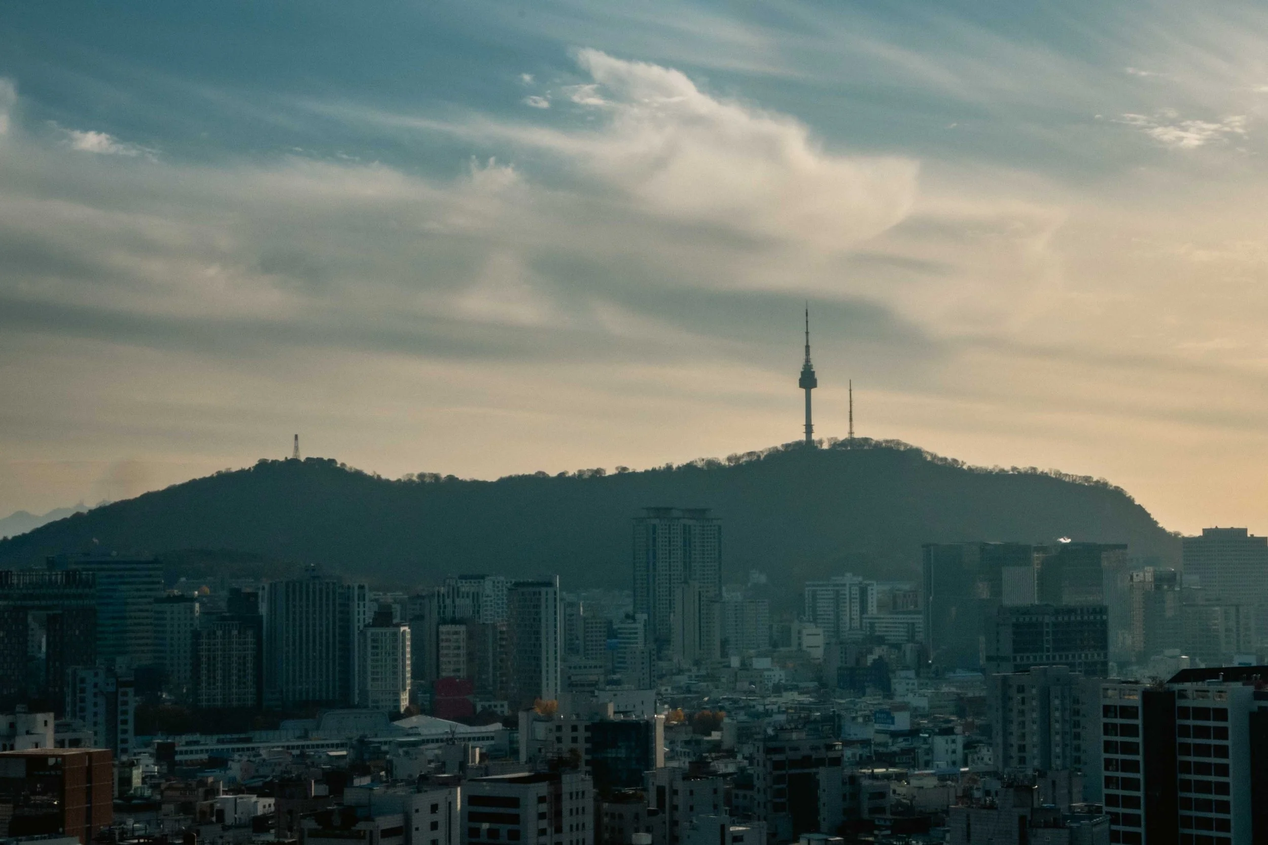 View over the city center of Seoul with its highrise buildings and the hill with the N-Seoul Tower in the background during sunset.