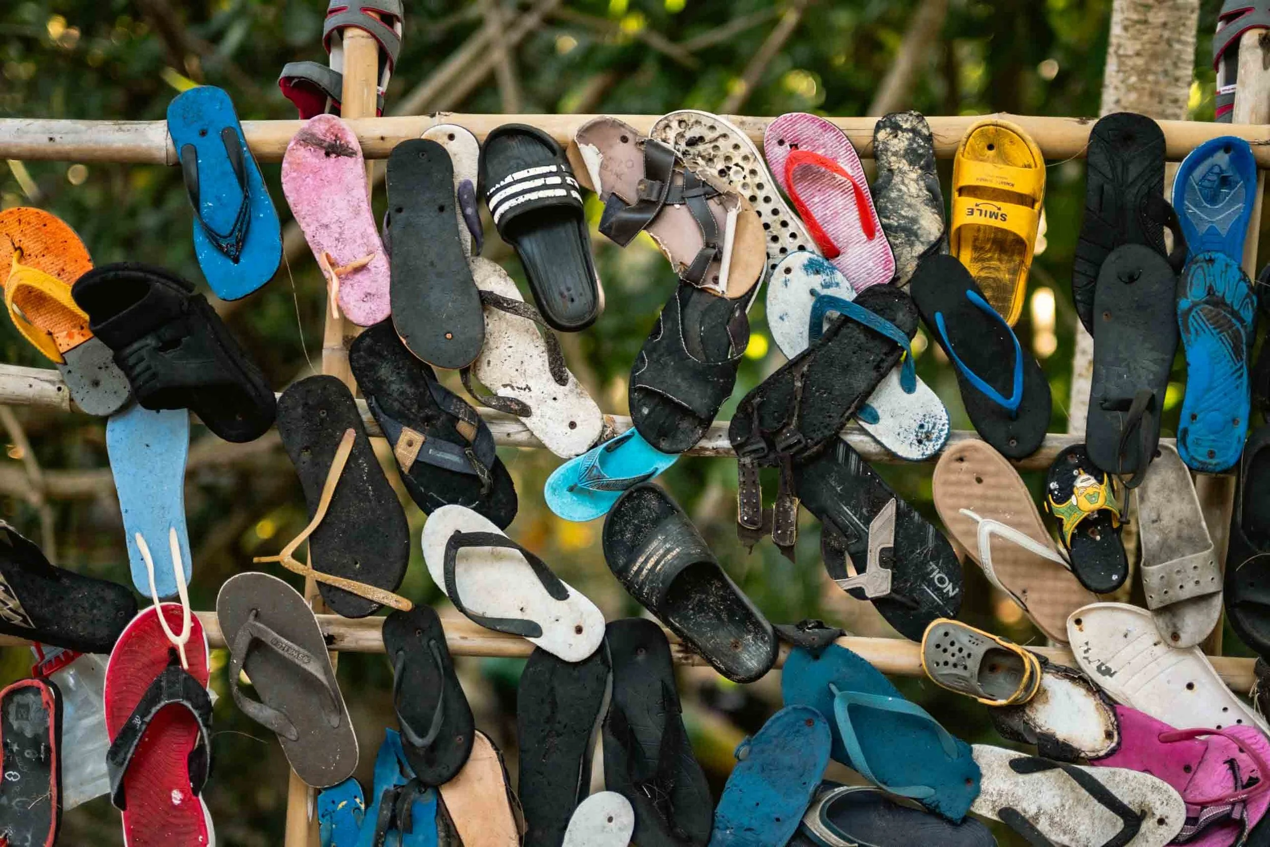 An art installation showcasing the rubbish problem of the ocean by hanging collected flip flops on a board.