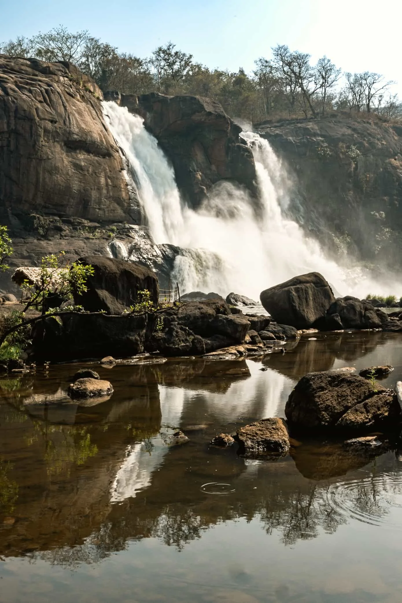 attirapilly falls reflecting on the water in a sunny day in India