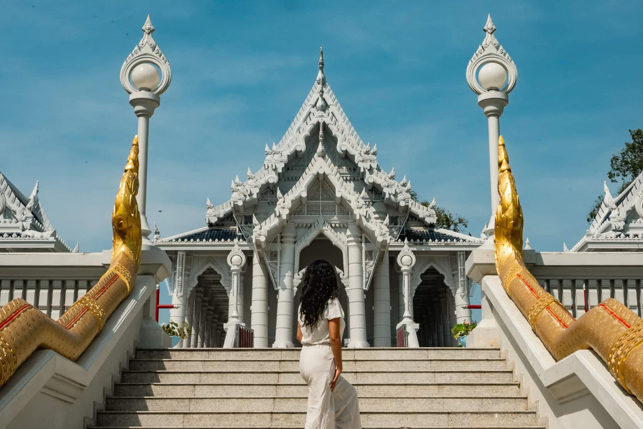 female tourist posing with her back towards the entrance of wat kaew korawaram in krabi thailand wearing a modest lightweight outfit respectful for thai temples.