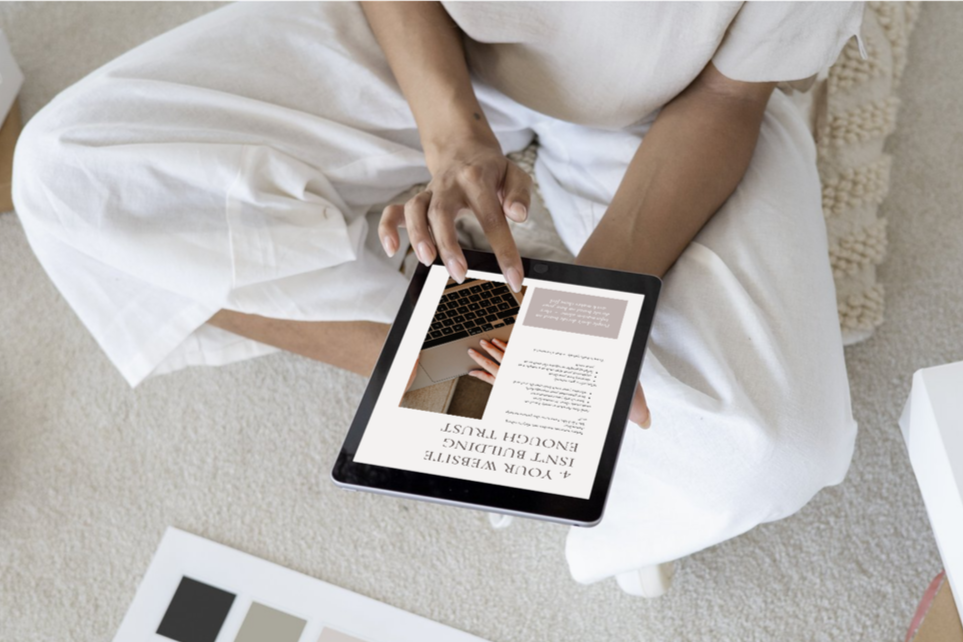 Person sitting on carpeted floor using a tablet to read an article about furniture design.