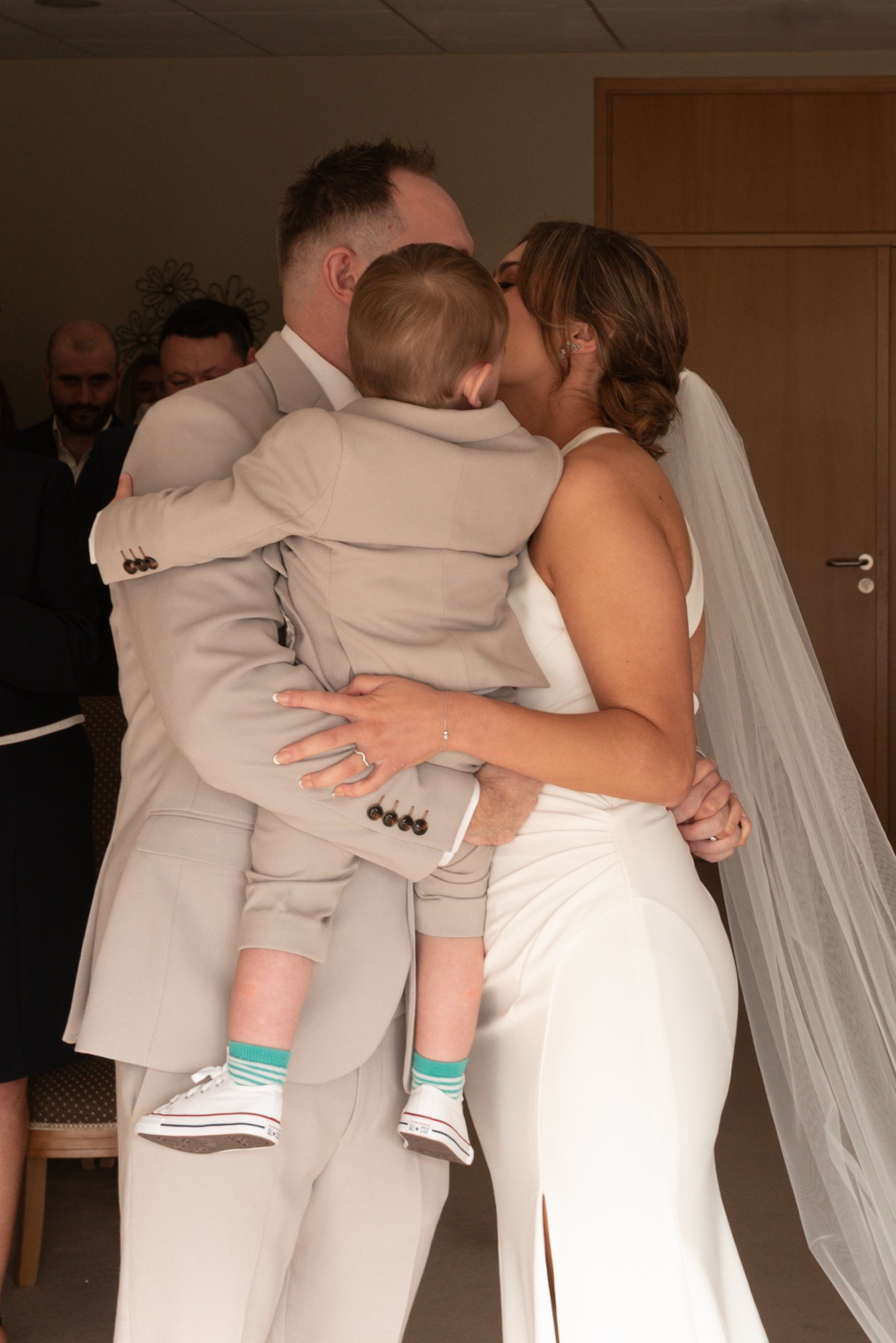 A couple share their first kiss as Mr and Mrs with their young child in their arms