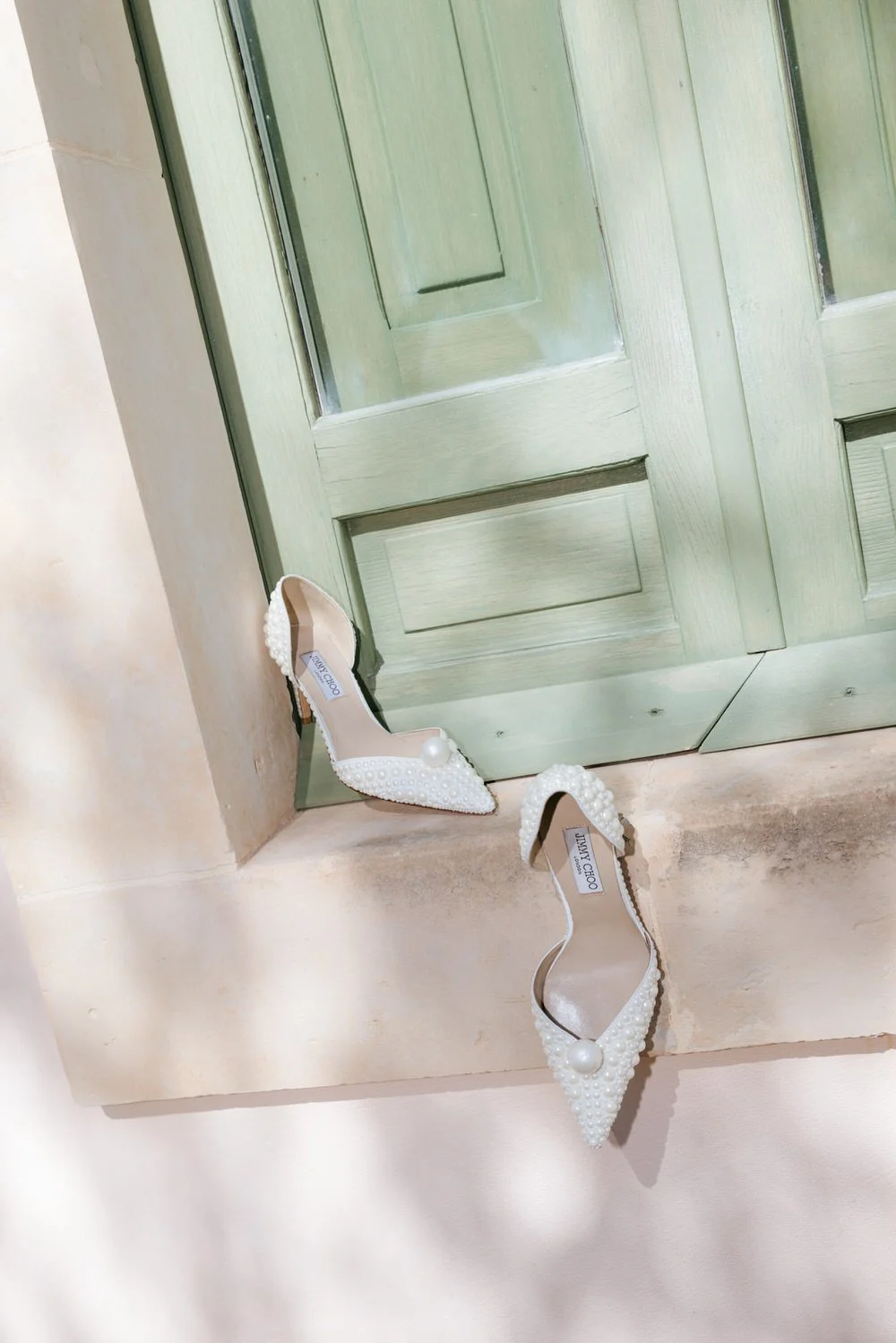 jimmy choo pearl-embellished bridal heels styled against a sage green shutter at a braccialieri wedding in sicily