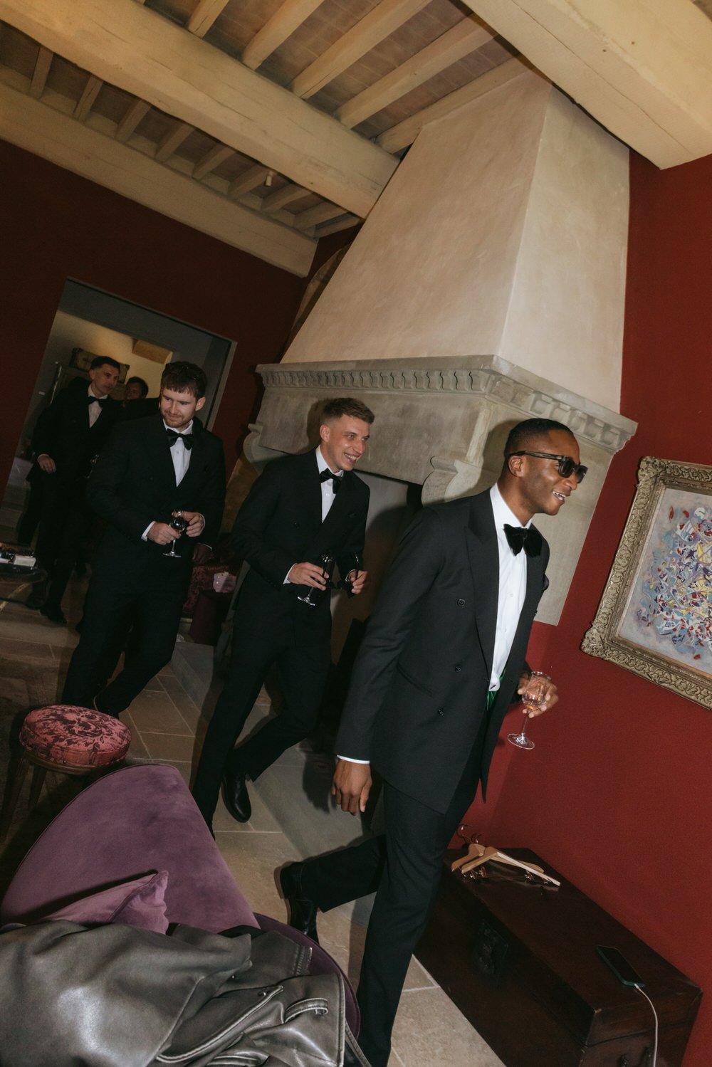 podere tesoro tuscany wedding photo of groomsmen candid moment inside a Tuscan villa, black tuxedos and champagne glasses creating a modern, stylish groom inspiration for a luxury destination wedding in Tuscany, Italy