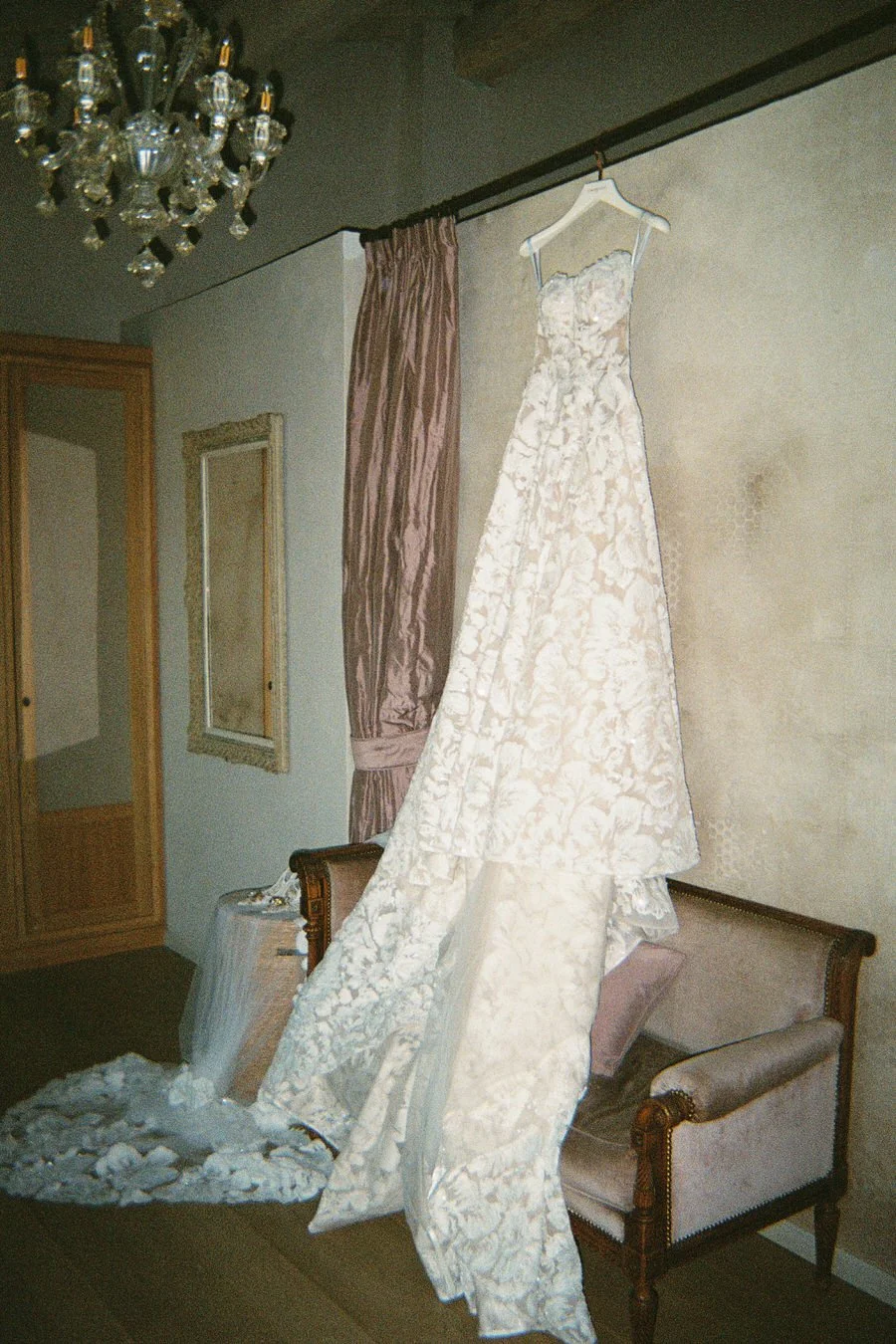 Ornate floral wedding gown captured on 35mm film, draped across a vintage loveseat in a softly lit suite at Villa Cetinale. A quiet, editorial moment from a Villa Cetinale Tuscany wedding
