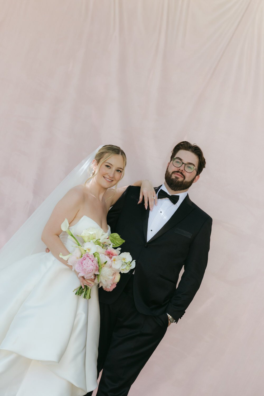 bride and groom at their palagina tuscany wedding, sharing a relaxed editorial moment against a soft blush backdrop