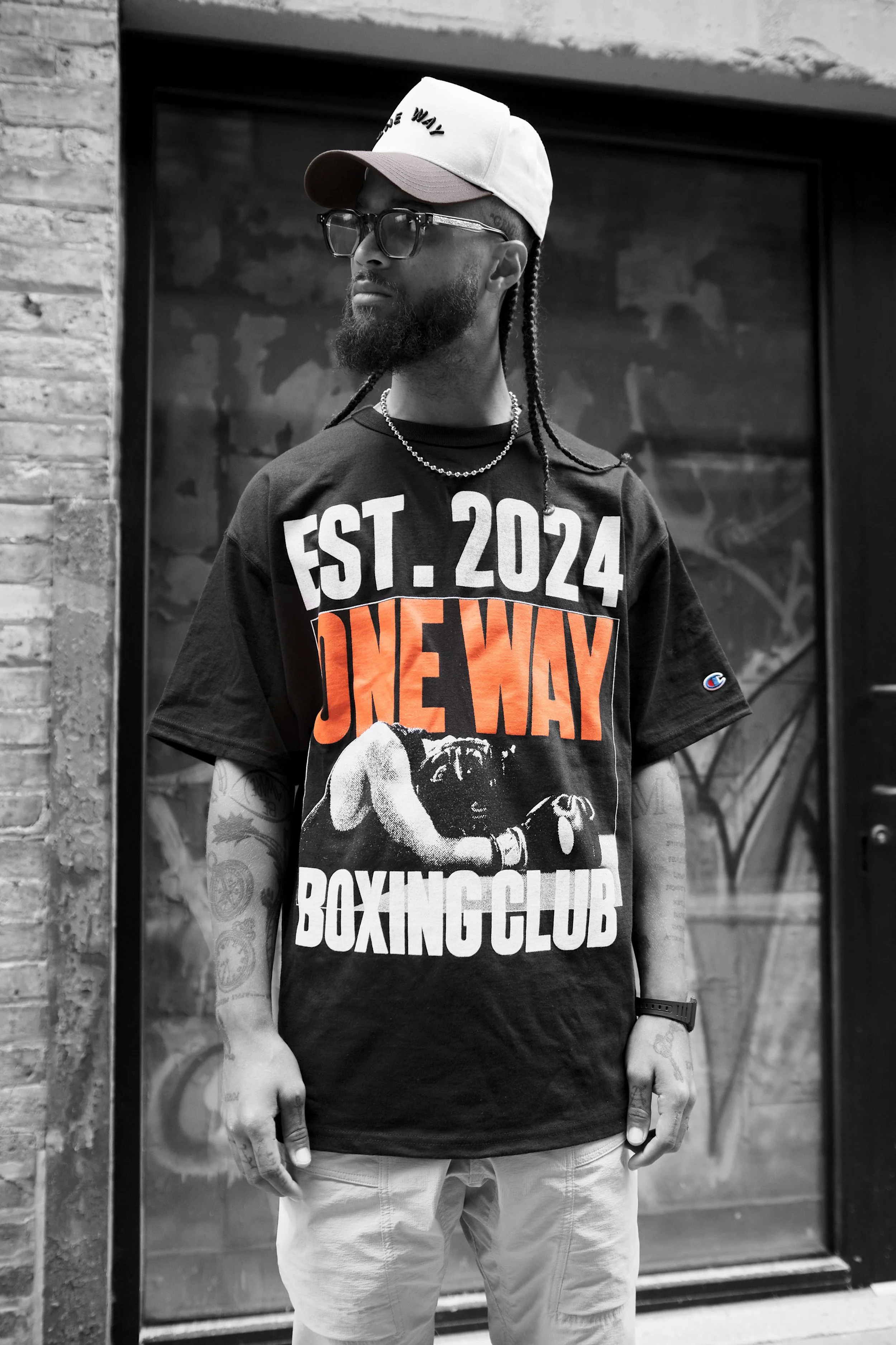 A model wearing the One Way Poster Tee outside a brick building.