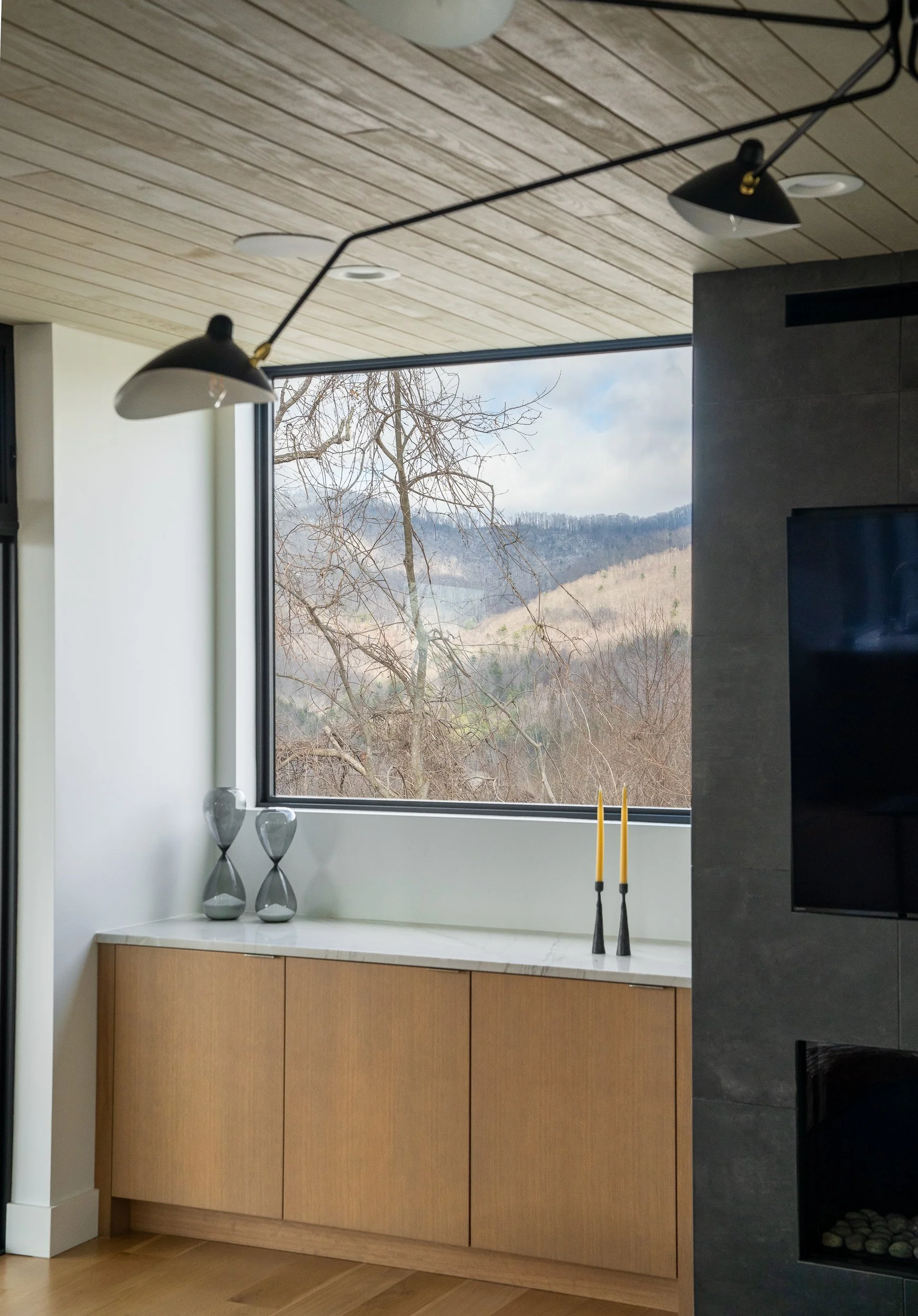 Detail of the living room window, ceiling light, built-in cabinet, and mountain view beyond the glass.