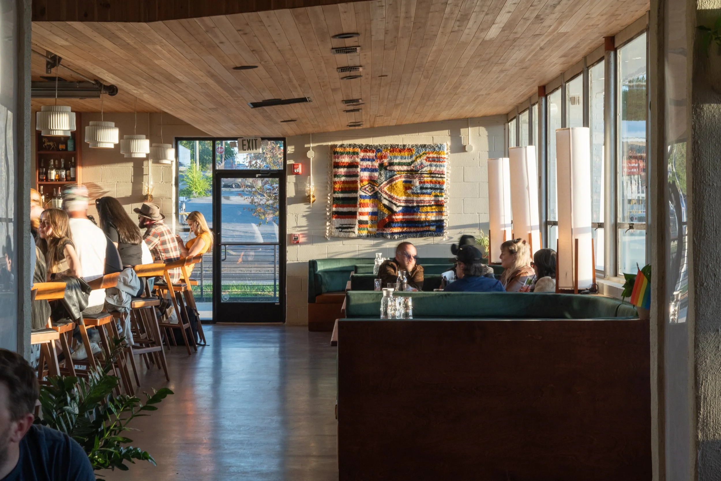 Interior view of a stylish cocktail bar with a woven textile wall feature and warm lighting.