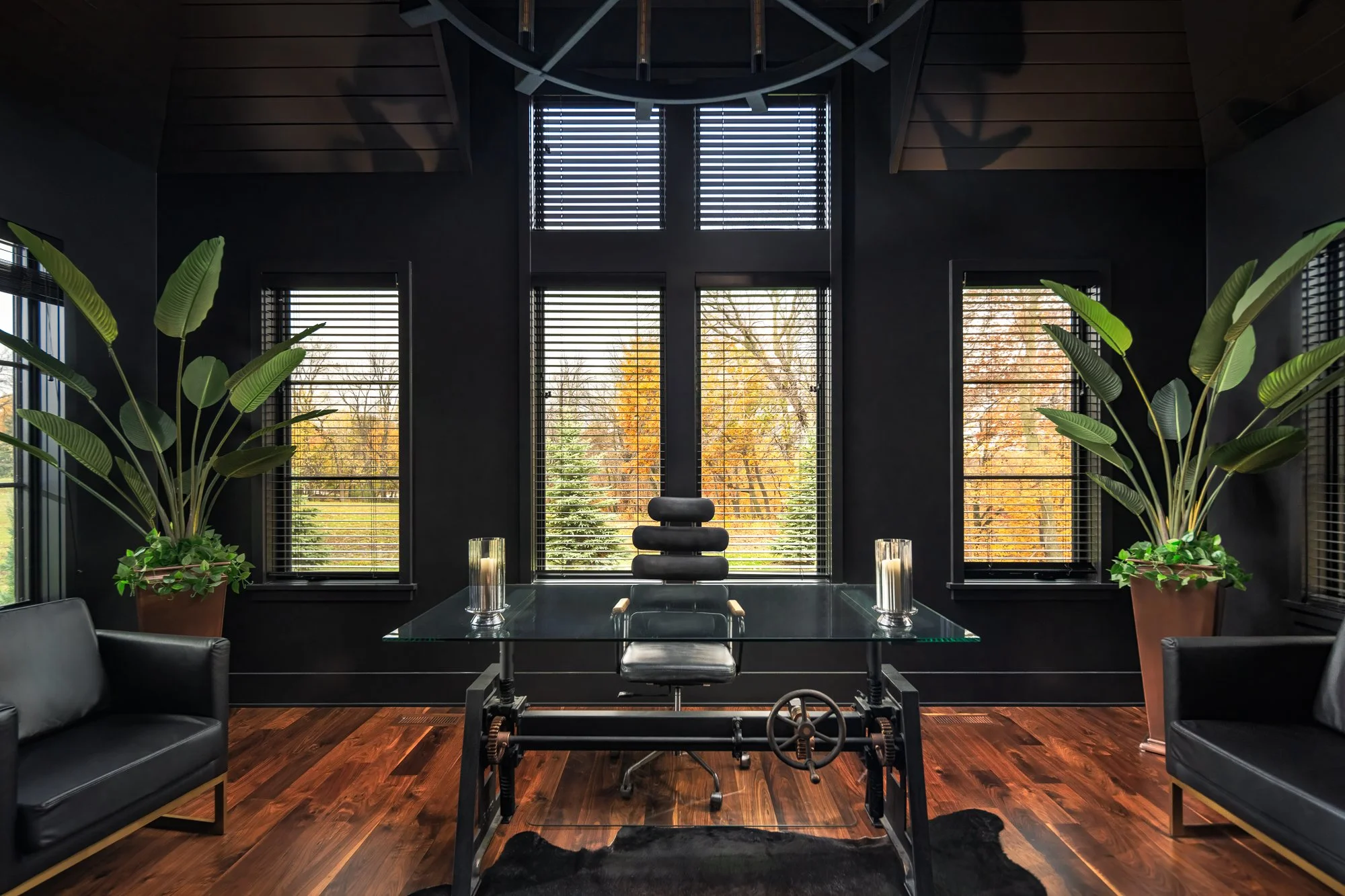 Luxury office with black walls, glass desk, and stylish furnishings.