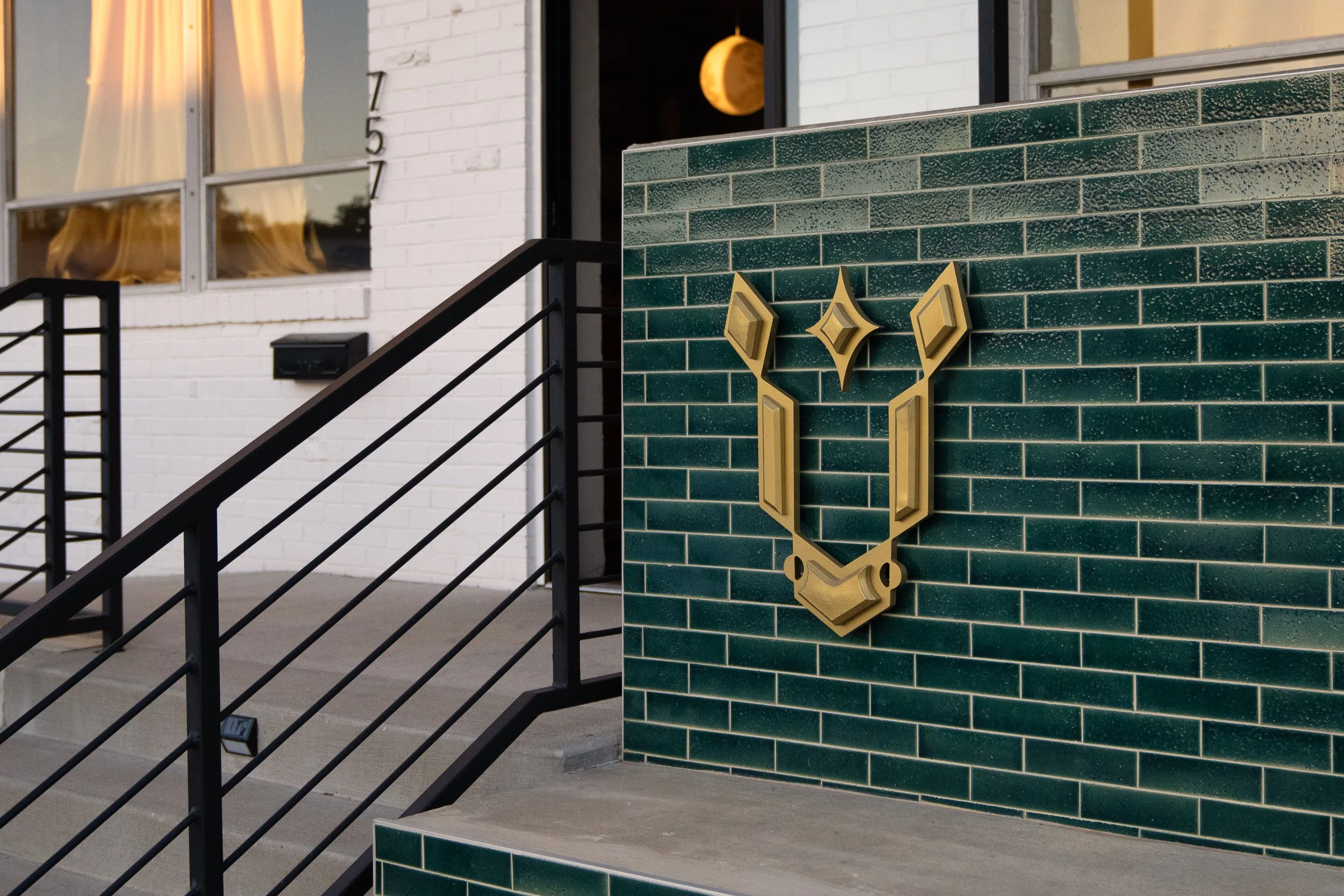 Green-tiled exterior wall featuring a golden geometric logo.