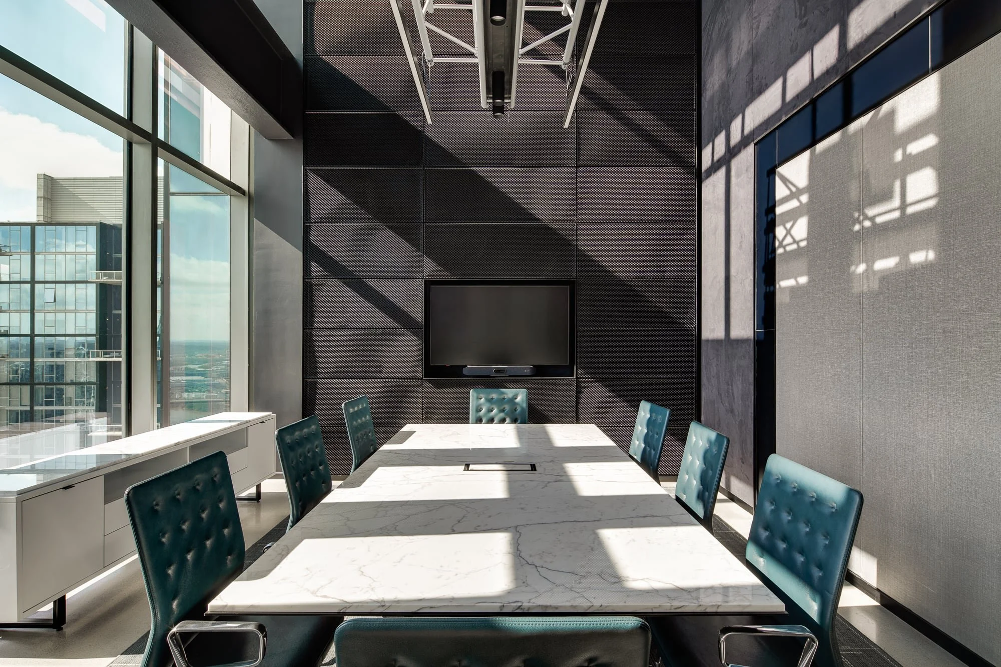 Alliance Bernstein Nashville boardroom with a marble conference table, tufted teal leather chairs, perforated metal accent wall, and floor-to-ceiling windows overlooking the city