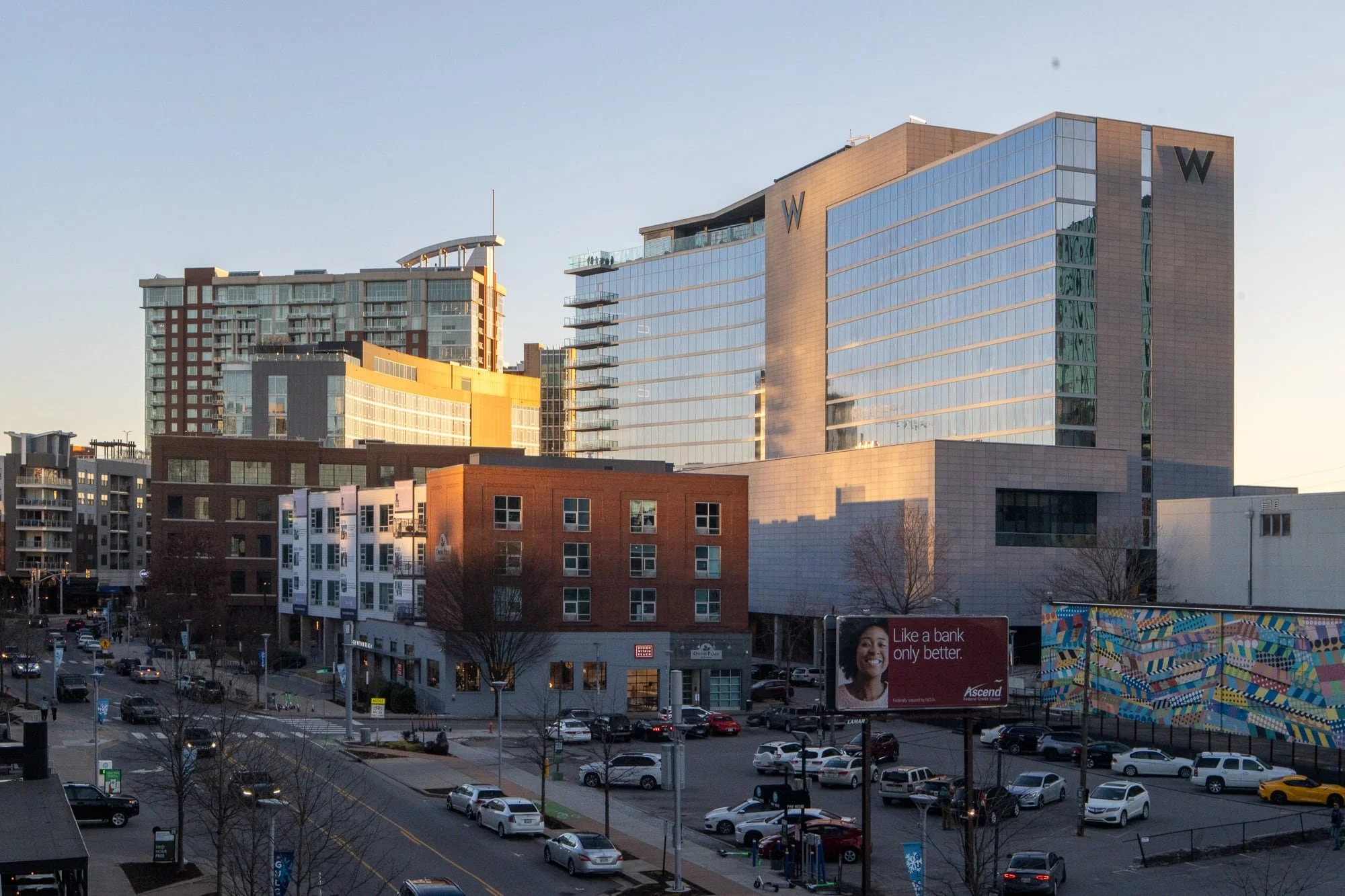 View of The Gulch neighborhood from the top of the Gulch Crossing stairs showing the W Nashville hotel, surrounding mixed-use buildings, street level activity, and a colorful mural on the right