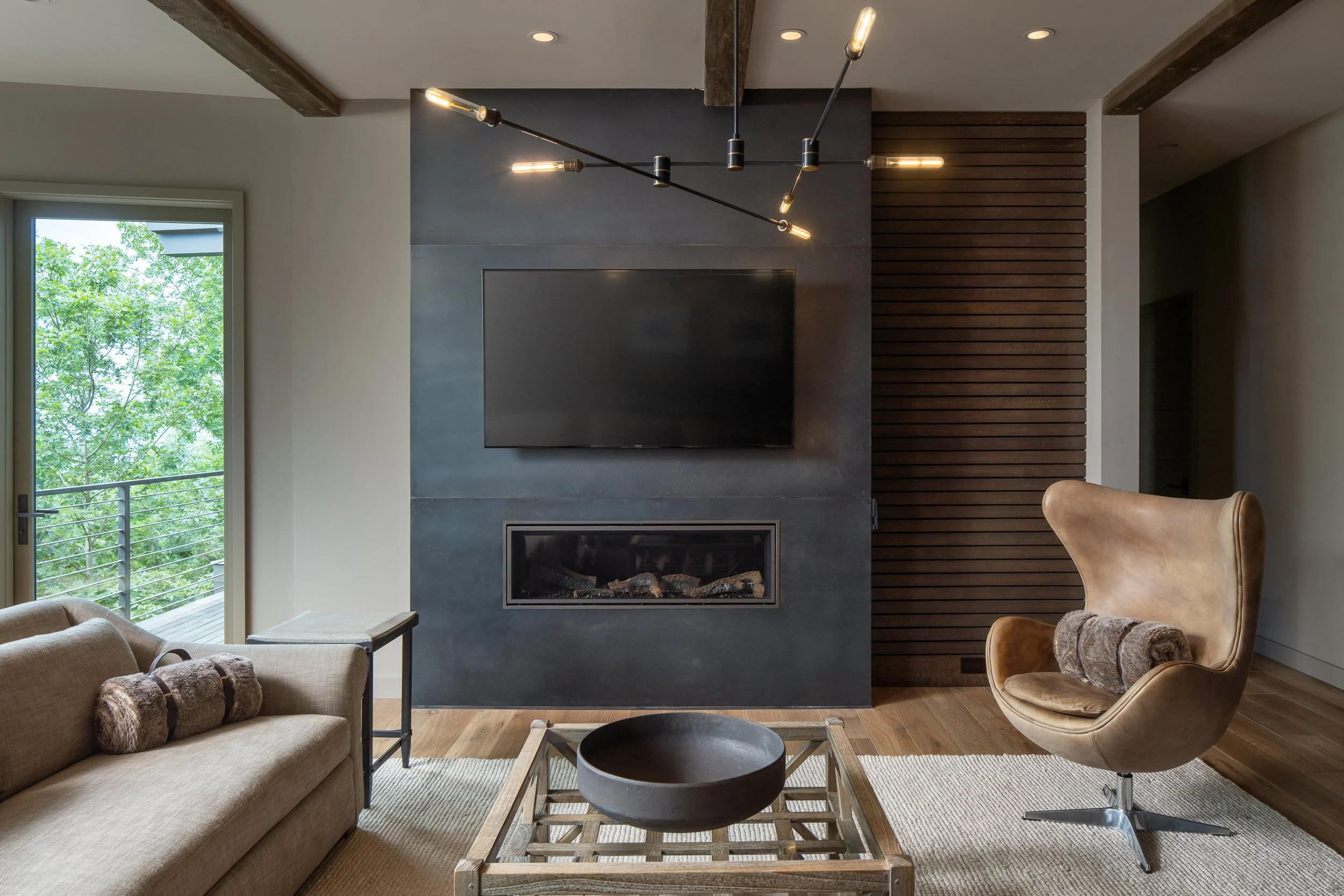 Living room with fireplace, modern seating, and large windows.