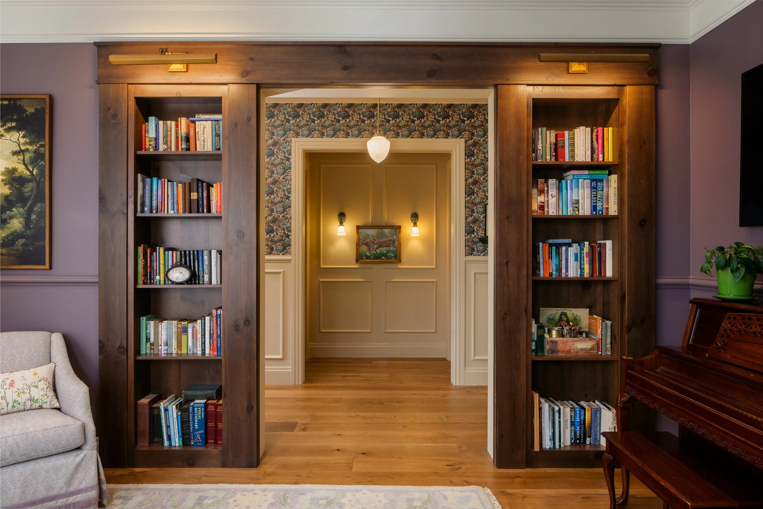 Wide passage framed by dark wood bookcases, wall sconces, and traditional trim