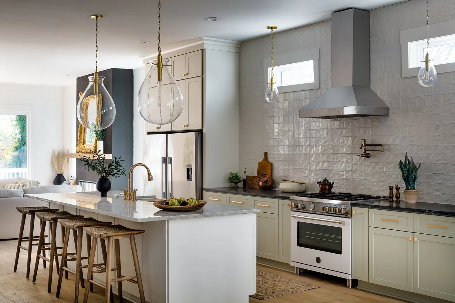 Modern kitchen with white island, pendant lights, stainless steel refrigerator, white cabinetry, black countertop, and minimal decorations.