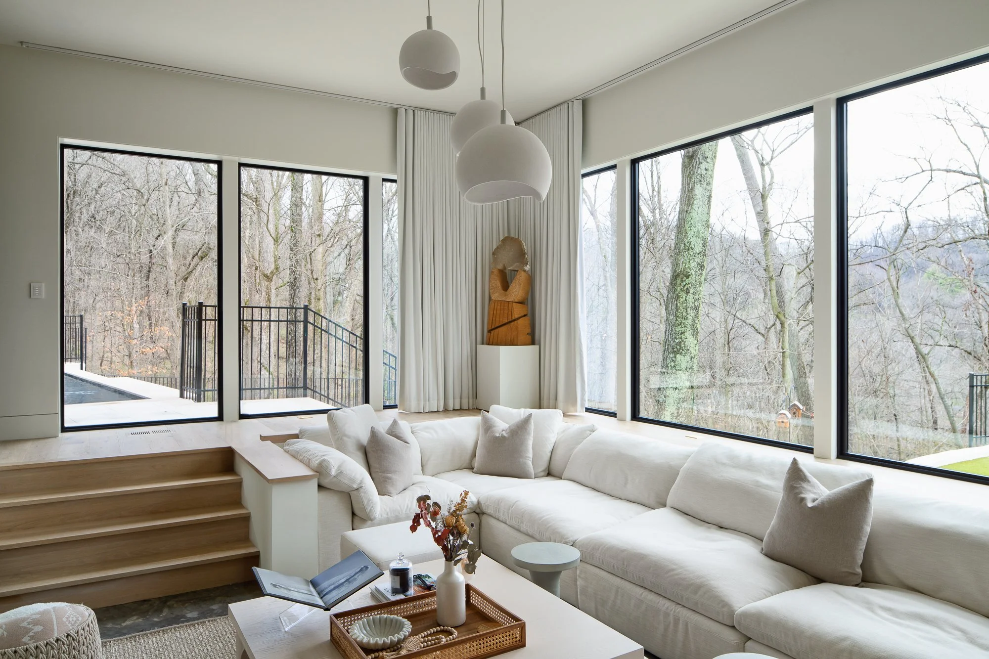 Sunken living room with wraparound sofa and floor-to-ceiling black-framed windows.