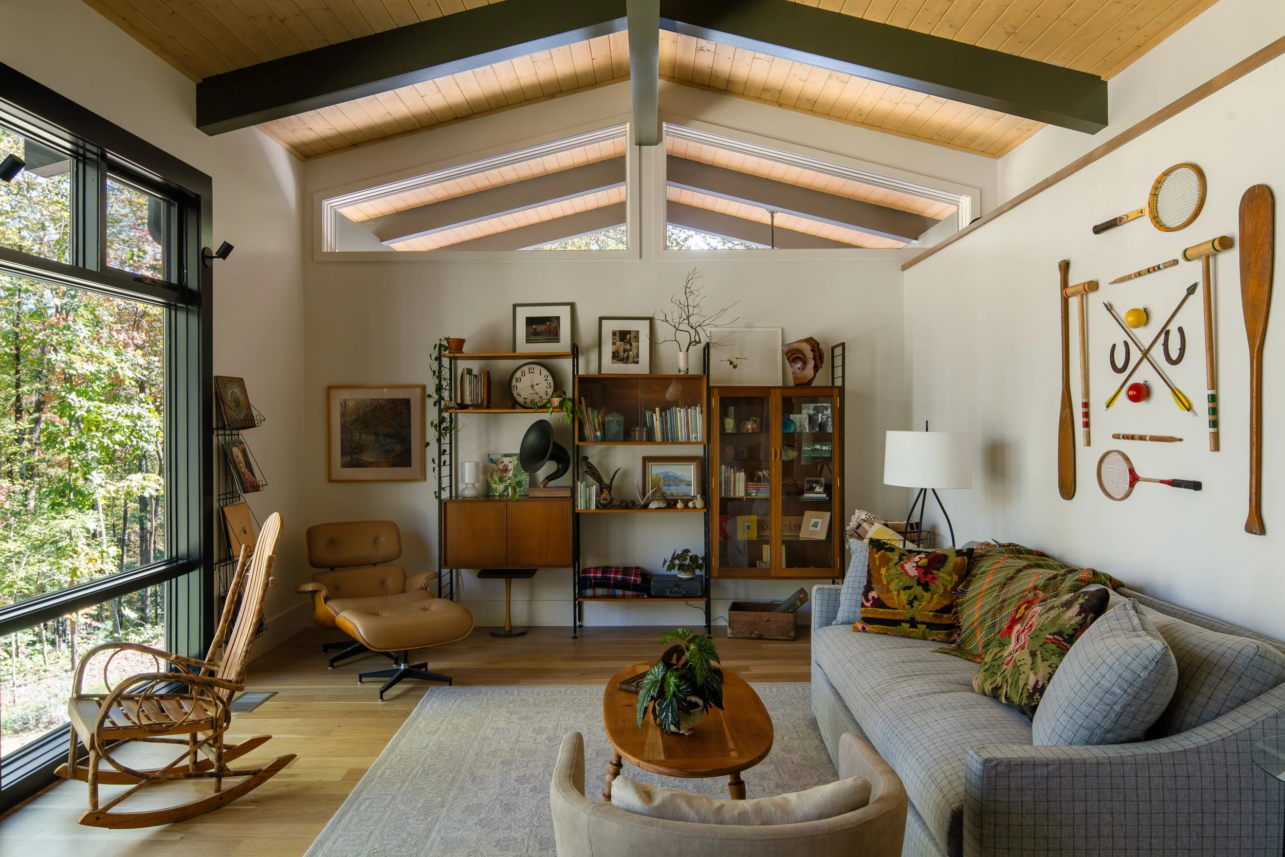 Living room with vintage furniture, high clerestory windows, and collected wall decor.
