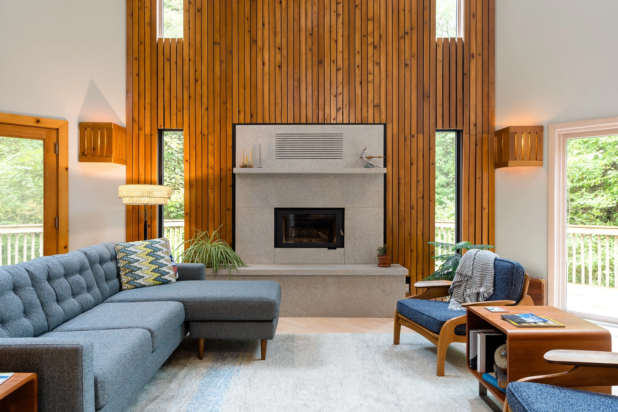 Modern living room with tall wood-paneled walls and a stone fireplace.