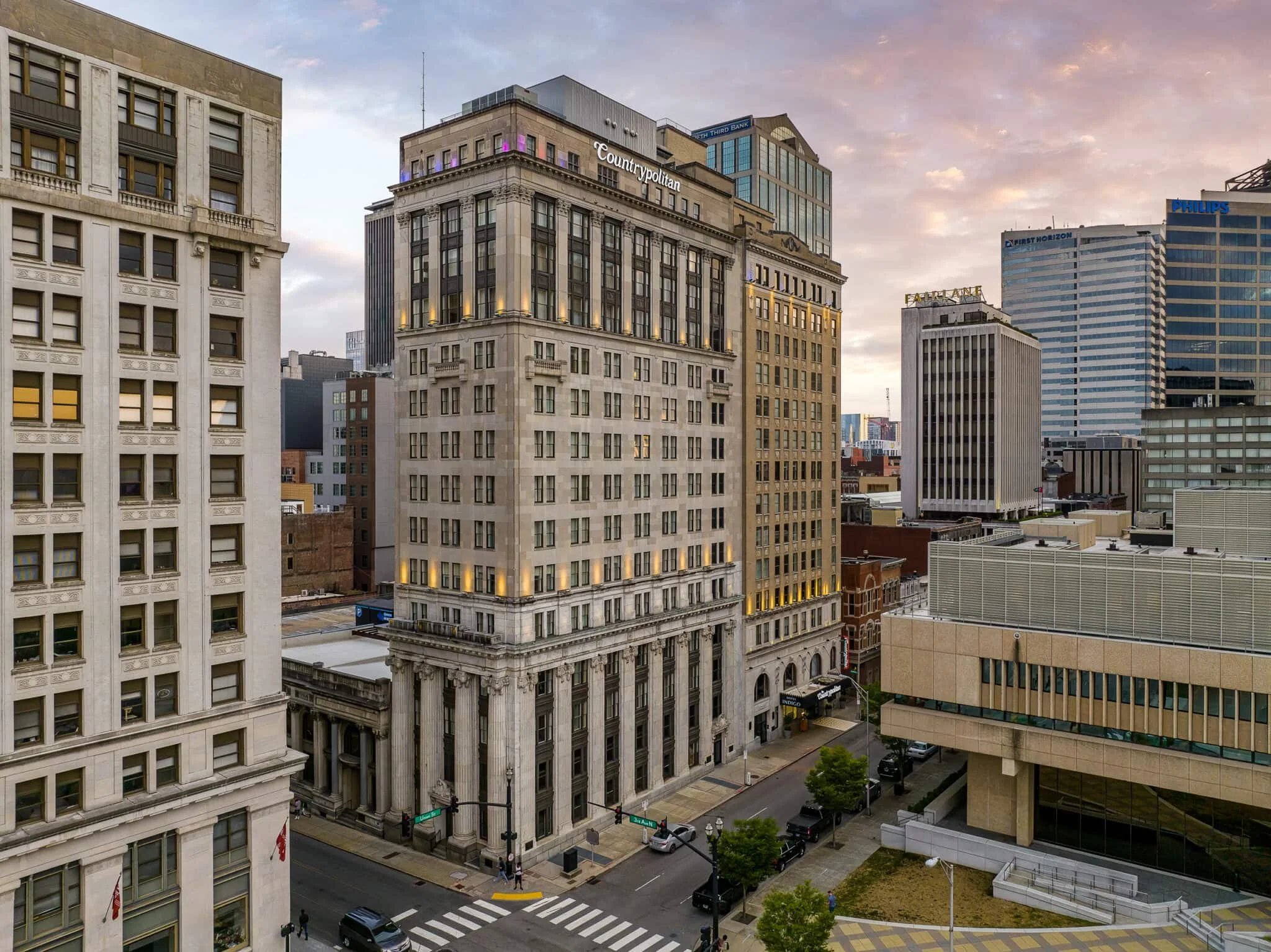 Elevated view of historic downtown buildings, including the Countrypolitan, with city towers and a soft evening sky.