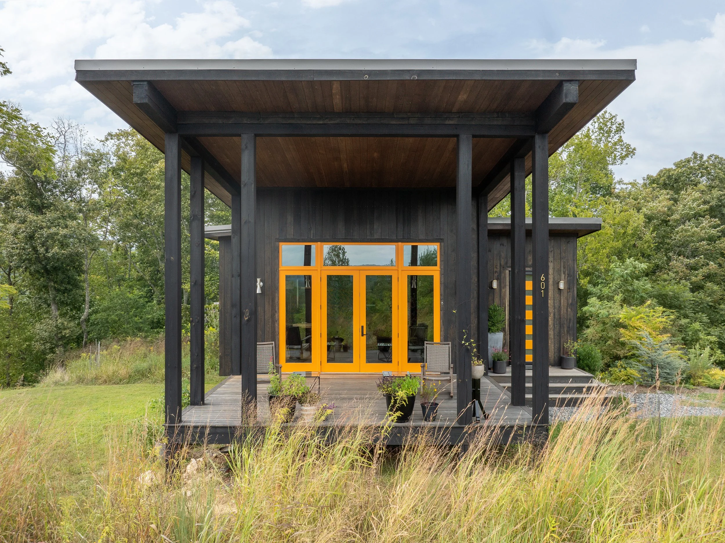 Black wood home exterior with a bright yellow door entrance.