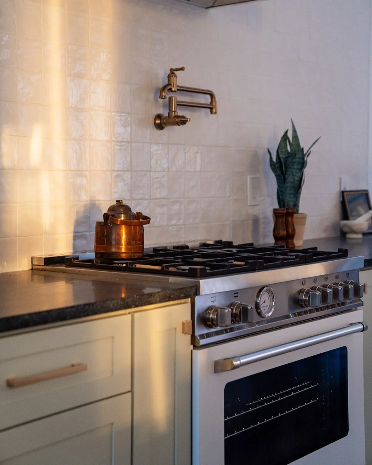 Kitchen stove with sunlit tile backsplash.