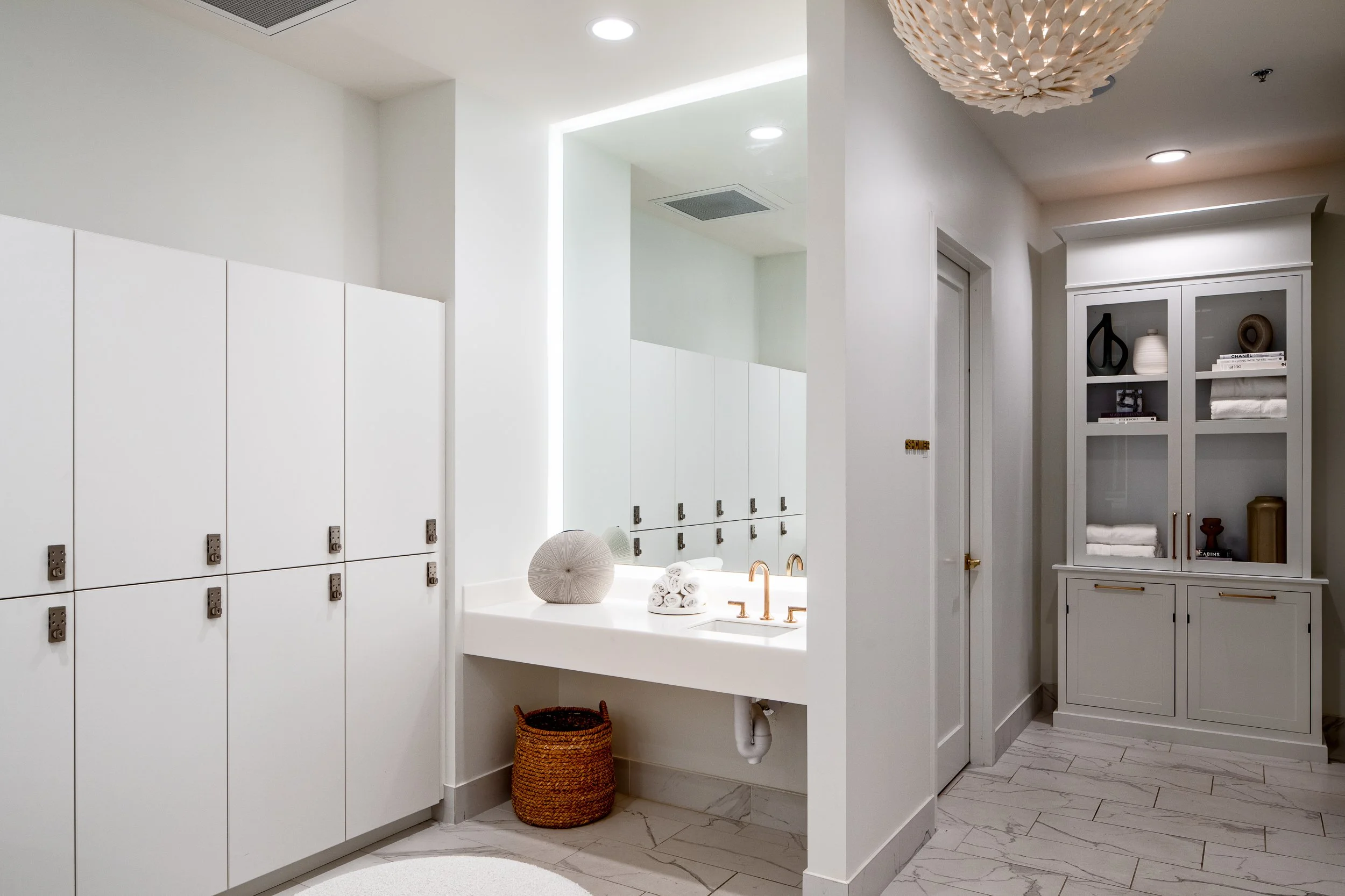 Locker room with spa-inspired details, including marble floors and white cabinetry.