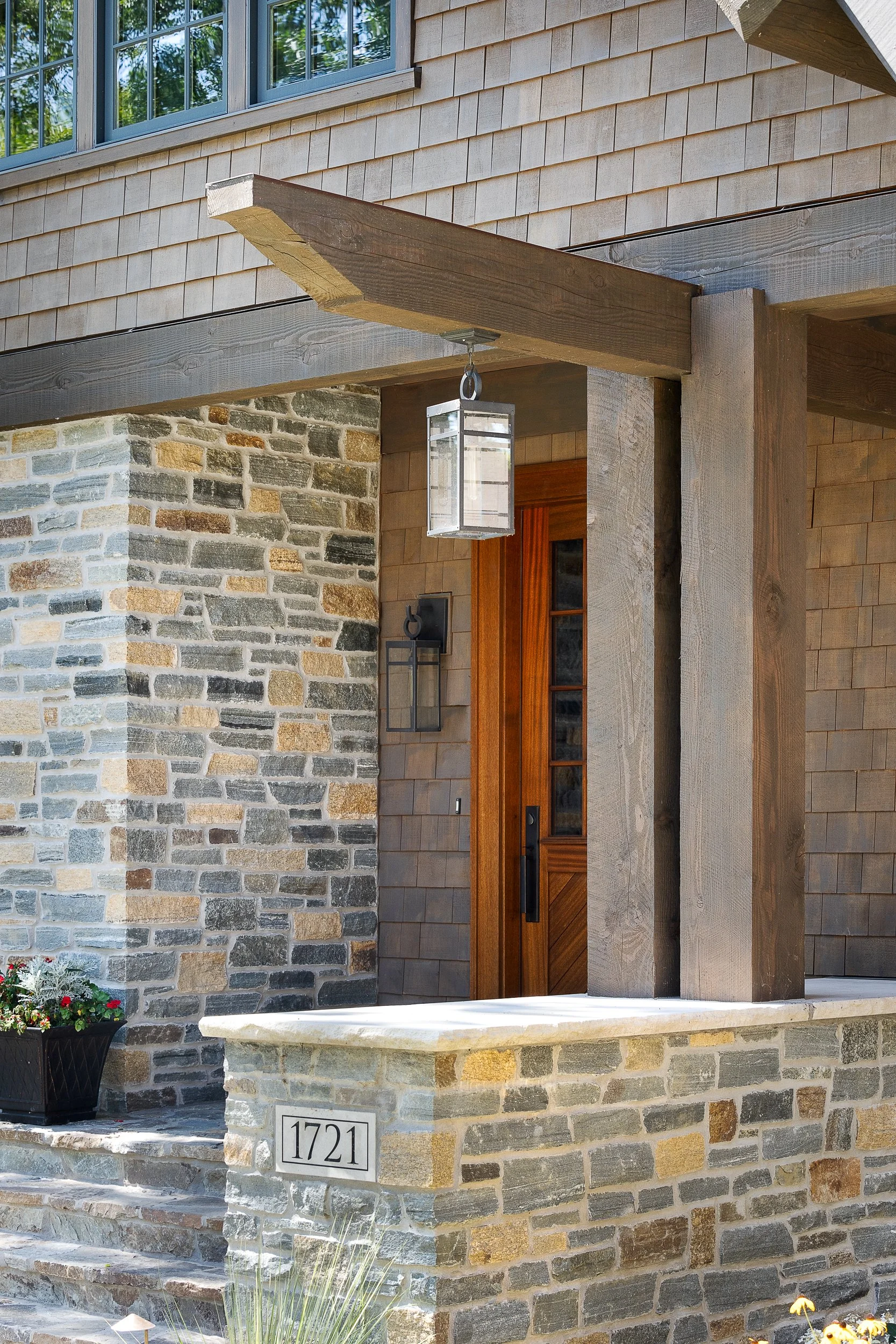 Wood post and beam entry porch with lantern light and stone accents.