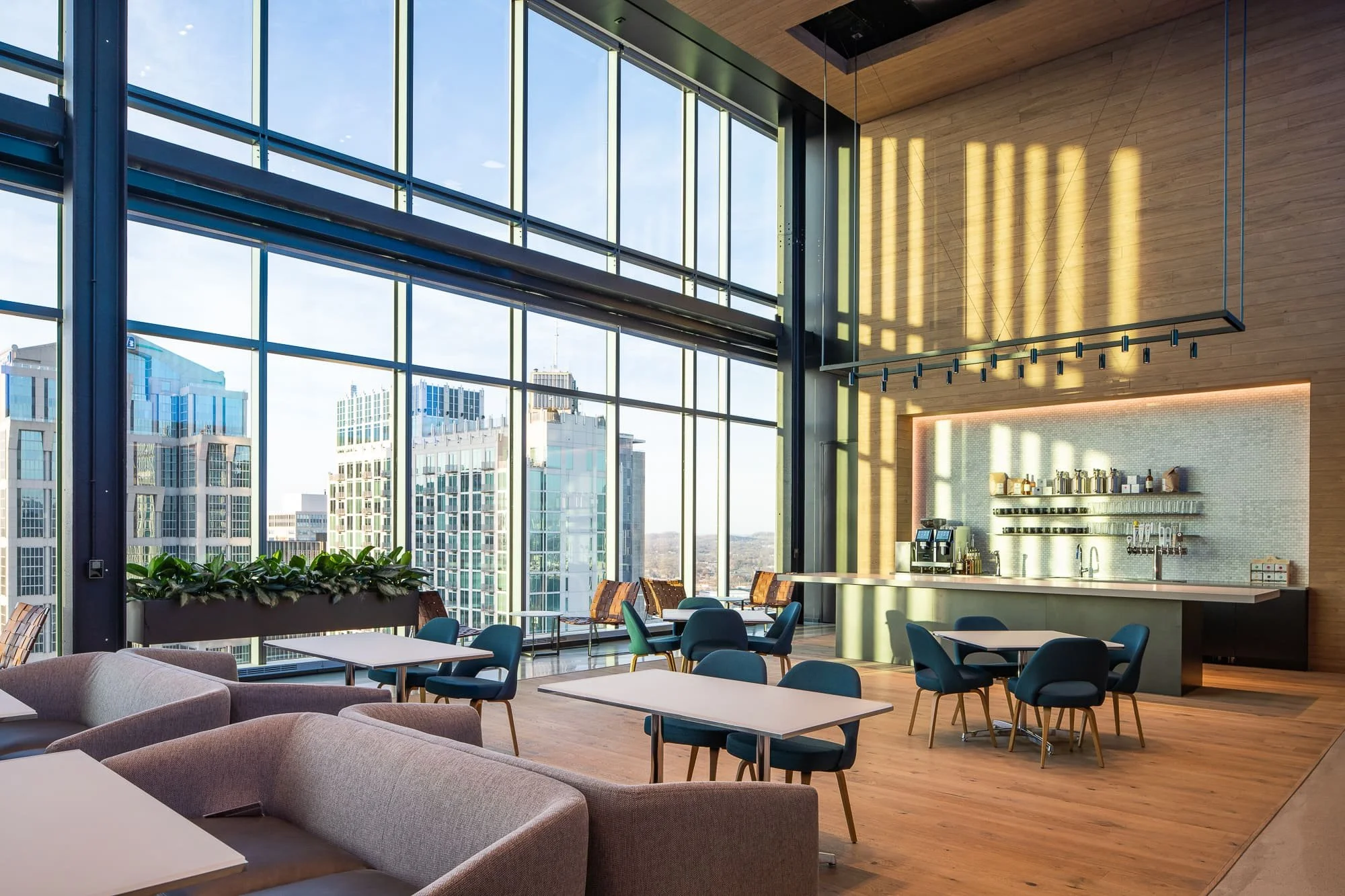 High-rise lounge with floor-to-ceiling windows, city views, wood walls, and contemporary seating.