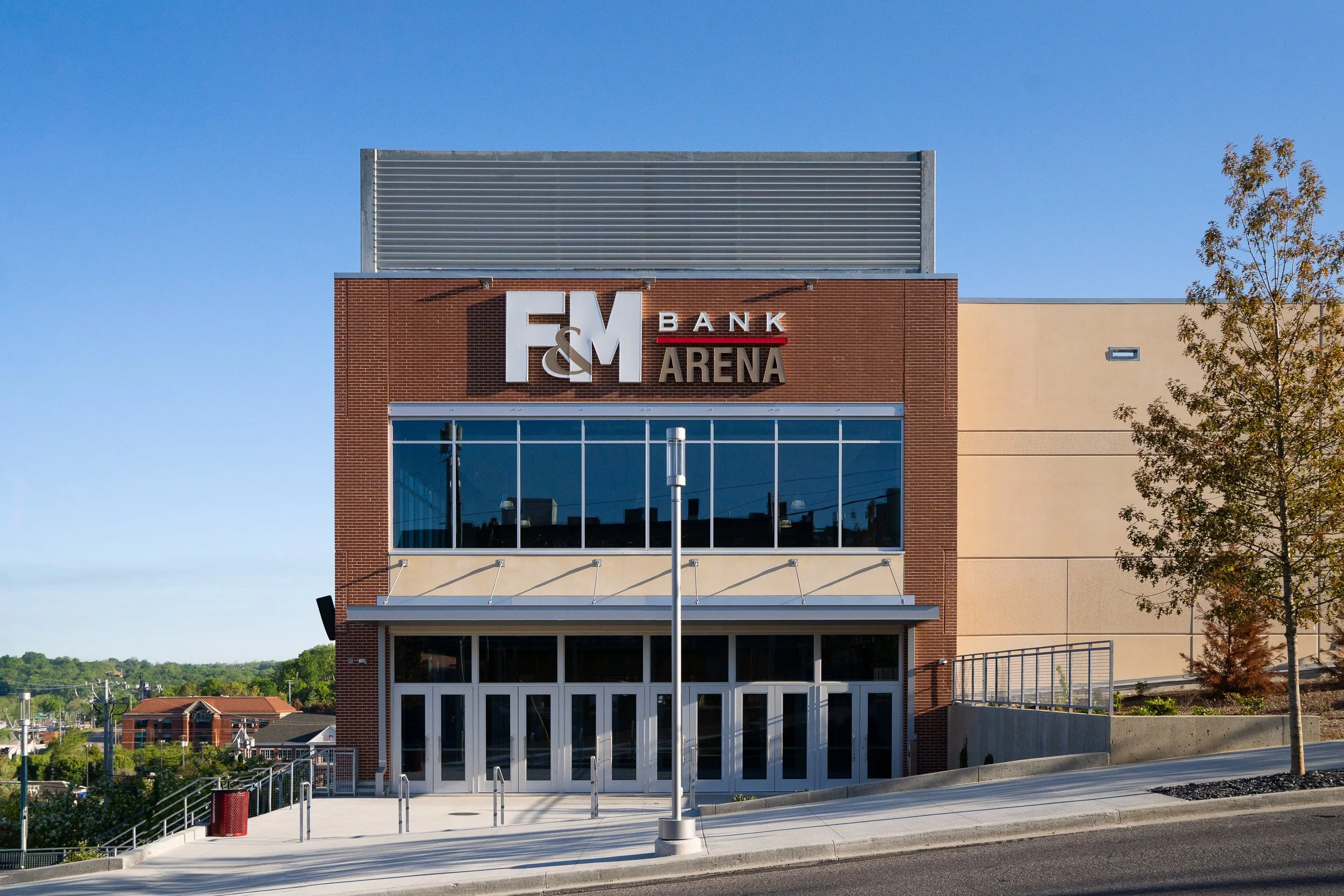 Front facade of a modern arena featuring large glass windows and brick elements.