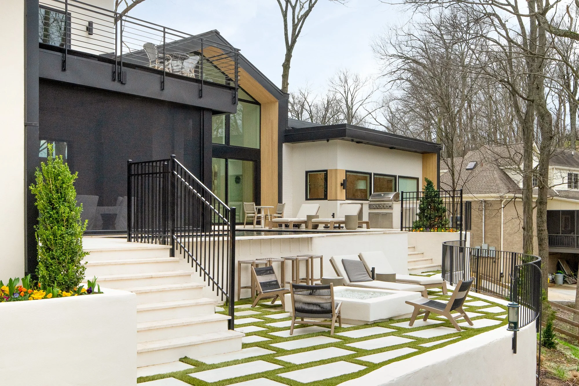 Outdoor terrace with lounge seating, grill area, and paver grid patio.