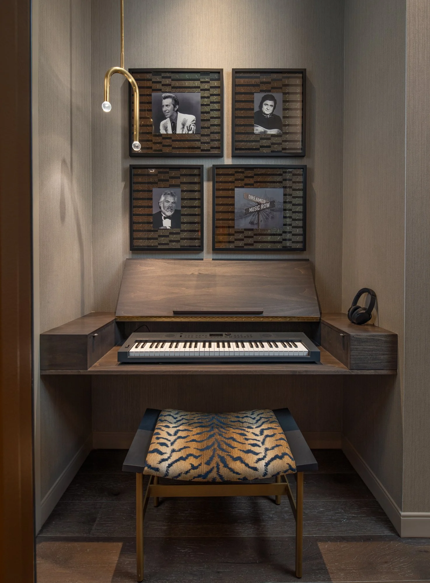Custom music alcove with a keyboard, upholstered bench, framed artwork, headphones, and sculptural brass lighting.