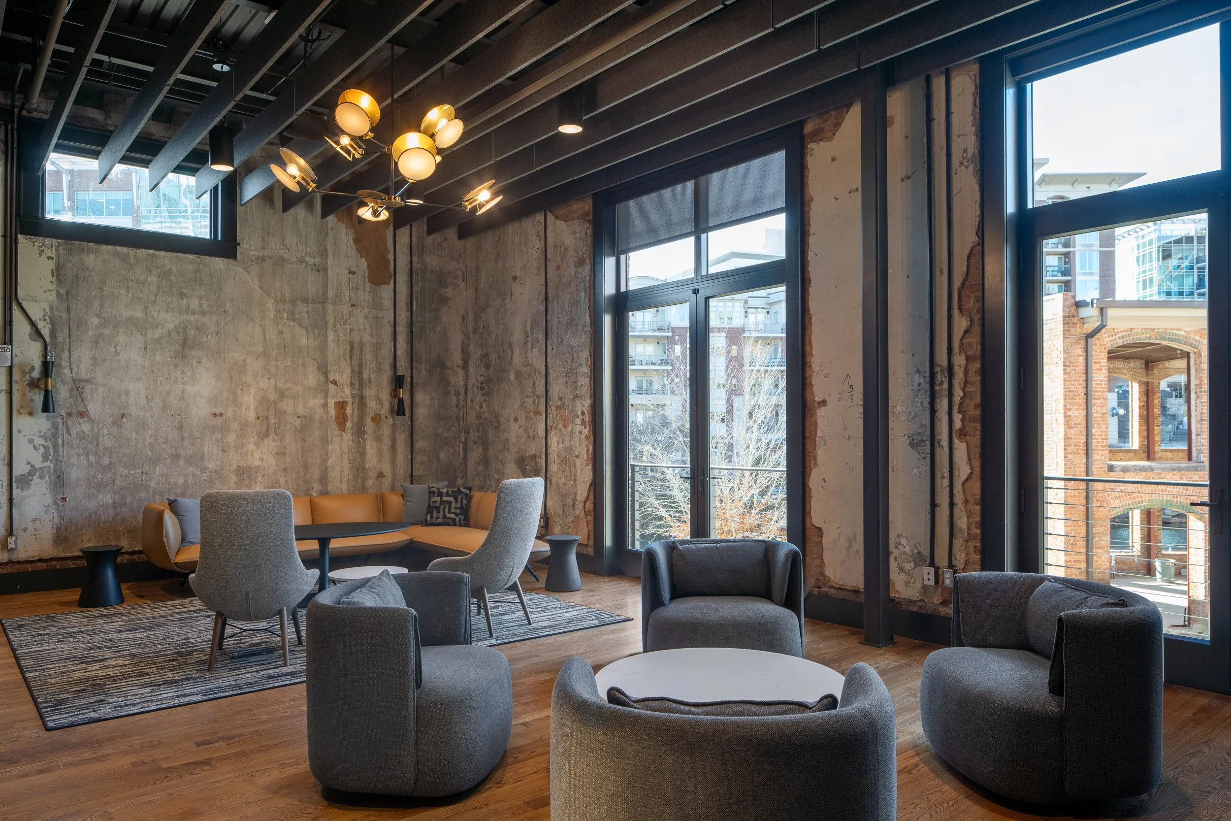 Green Room with worn original plaster walls, gray swivel chairs, a leather banquette in the corner, and balcony doors opening to downtown views.