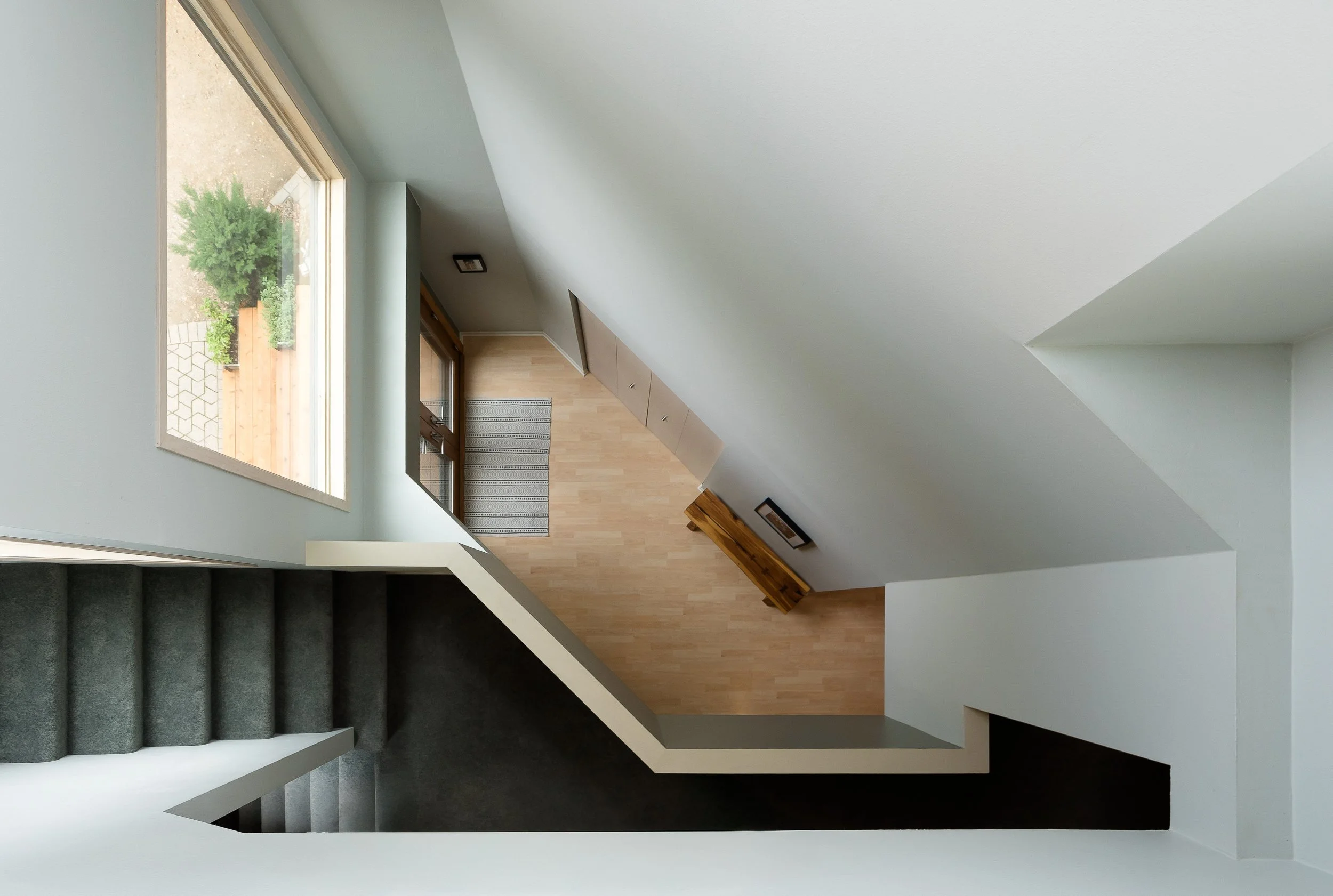 Bright stairwell with clean white walls, wood flooring, and geometric architectural lines.