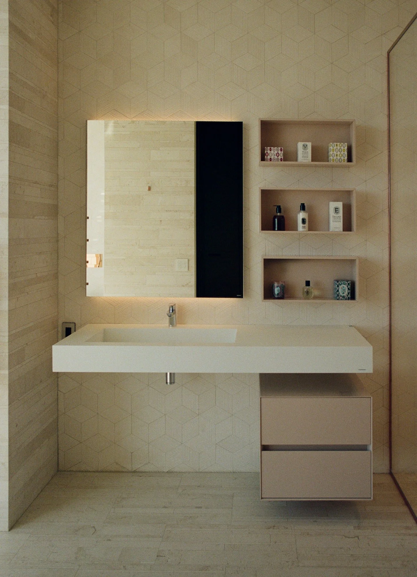 Minimal powder bath with a floating sink, backlit mirror, recessed shelves, and geometric textured wall tile.