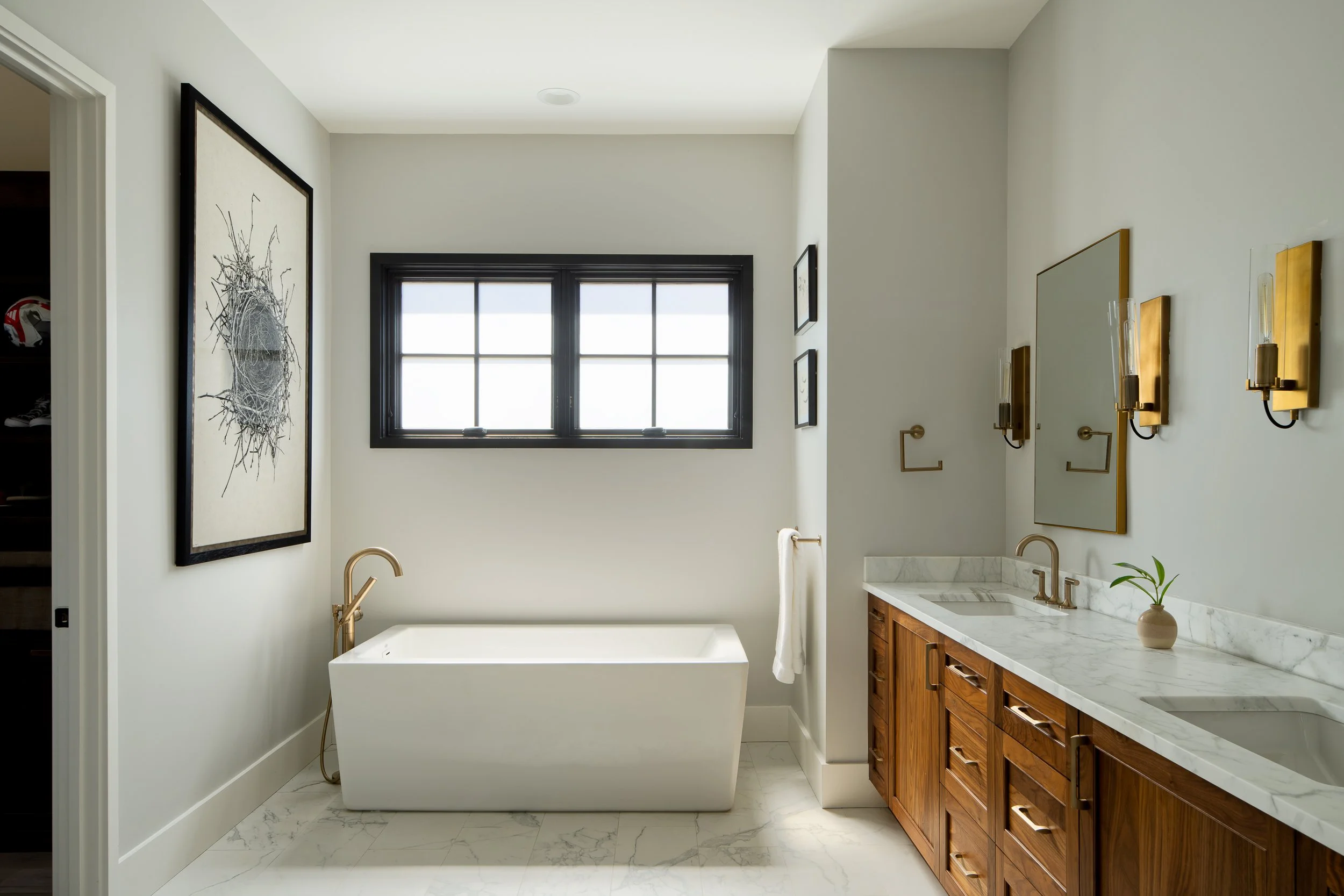 Bathroom with a freestanding tub, wooden vanity, and marble details.