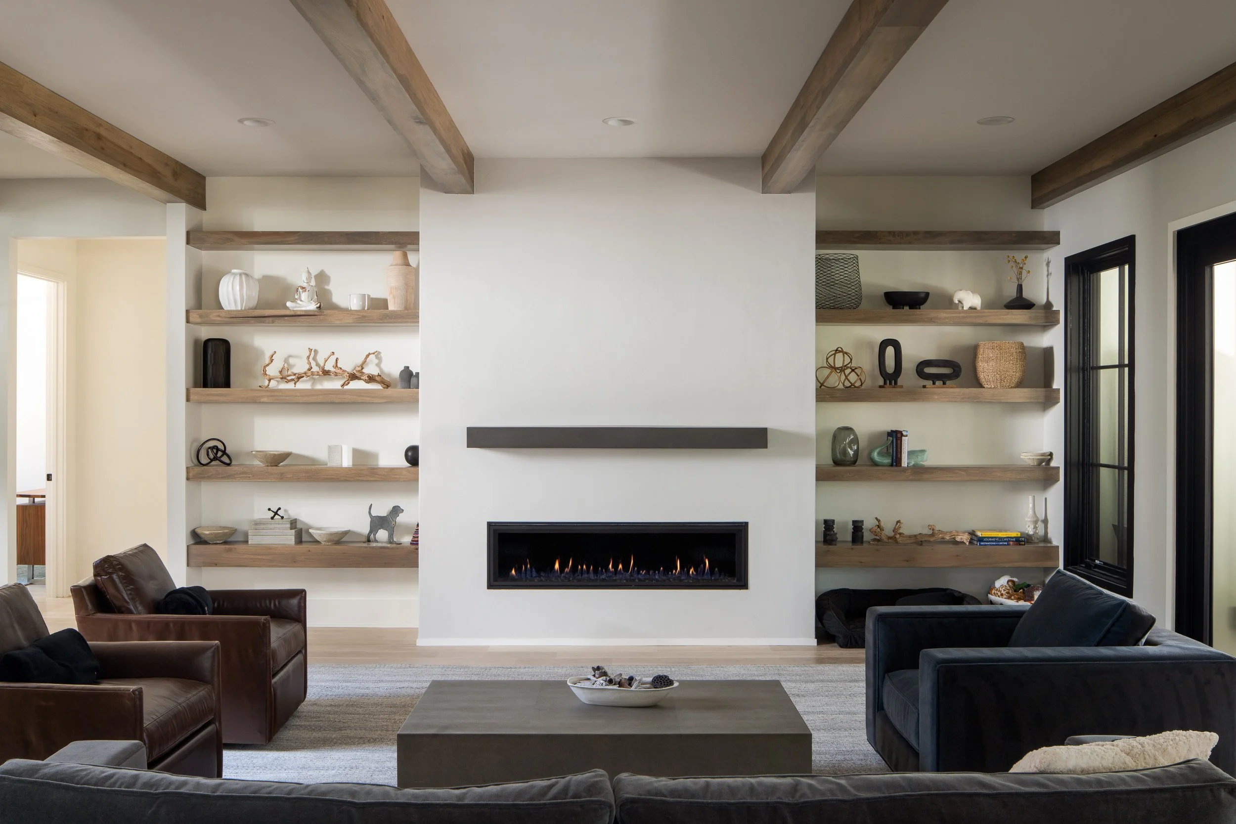Living room with floating wooden shelves and a linear fireplace.
