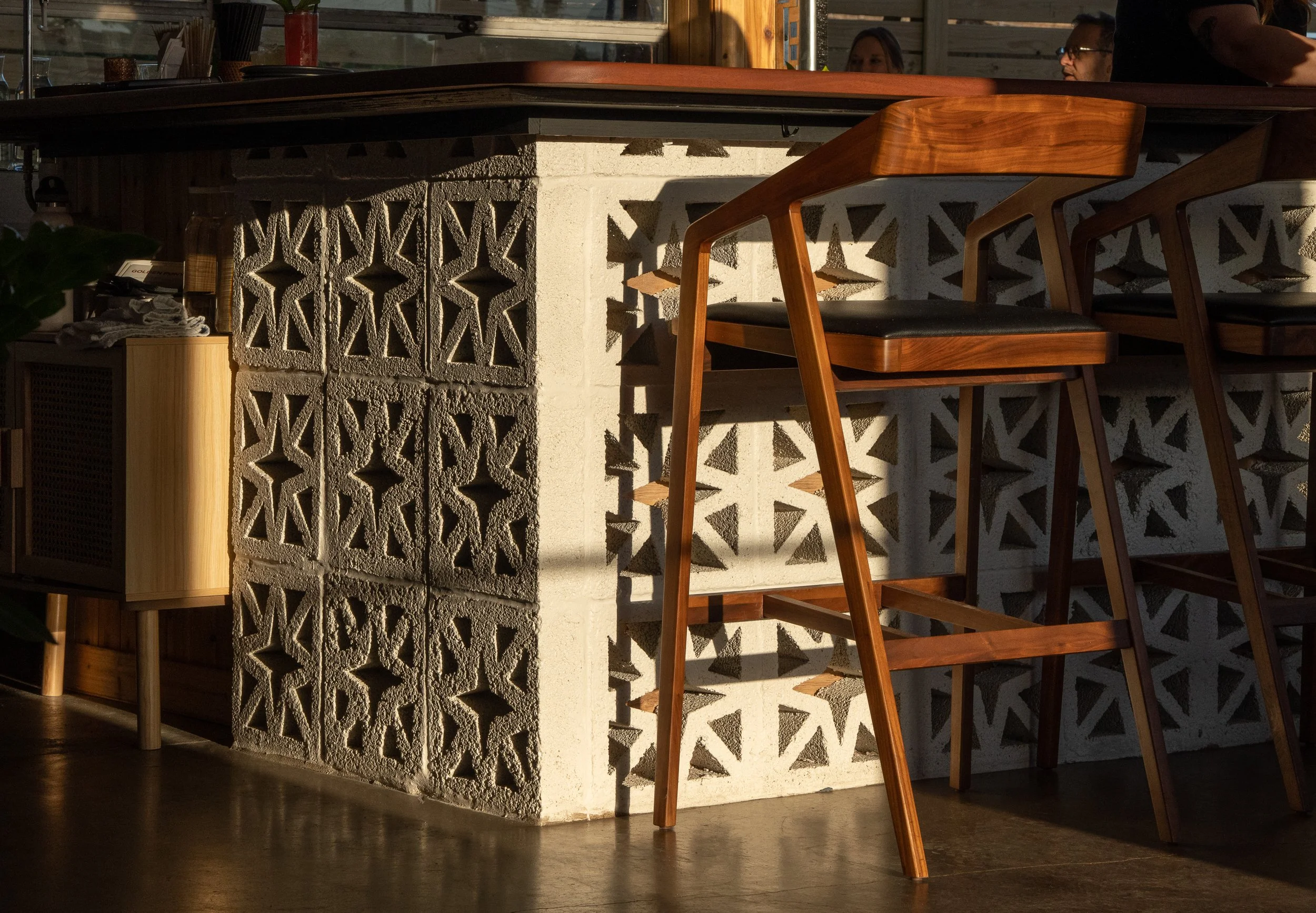Close-up of bar counter with decorative brickwork and wooden barstool.
