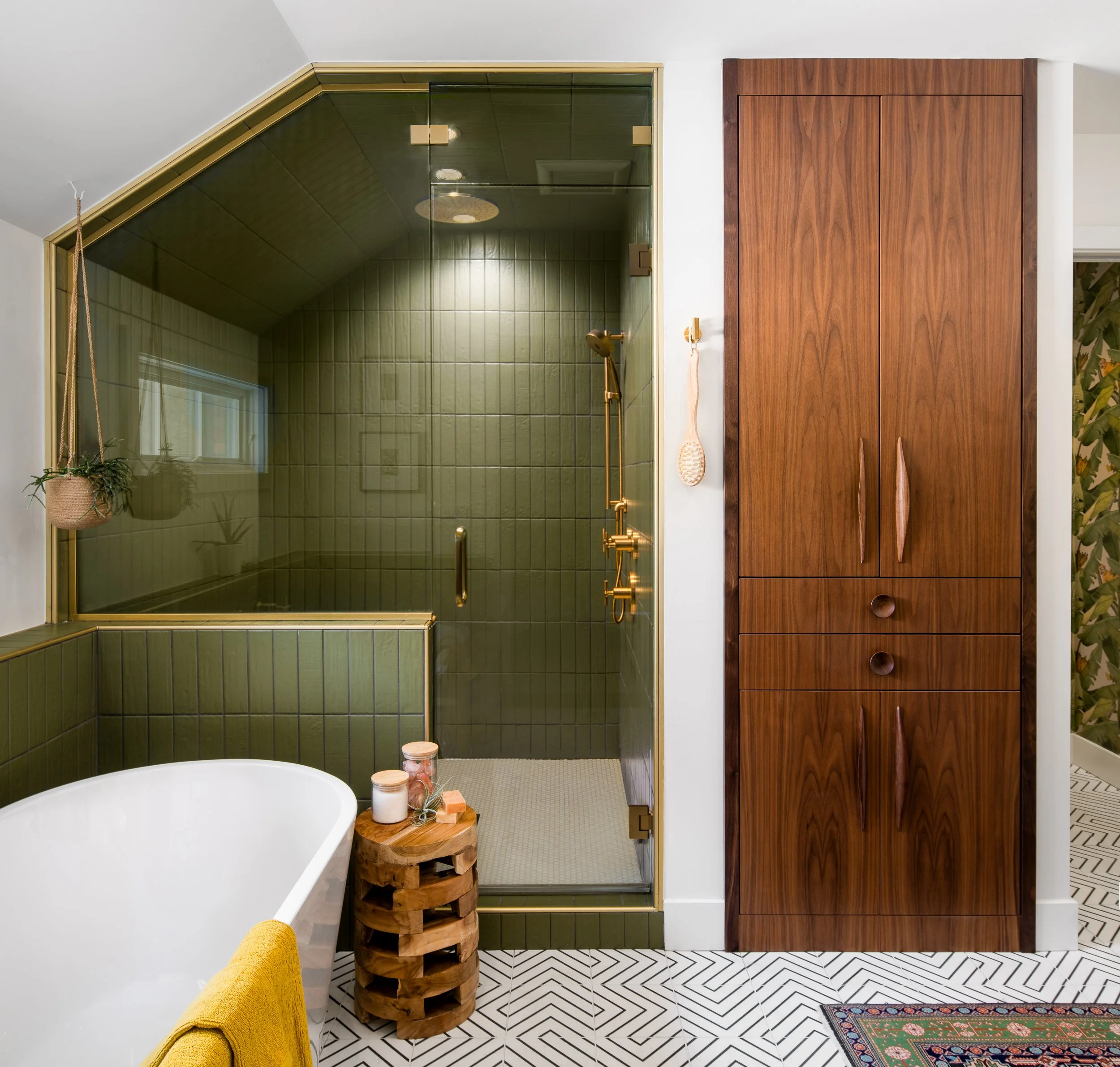 A bathroom with a green-tiled shower and walnut cabinetry.