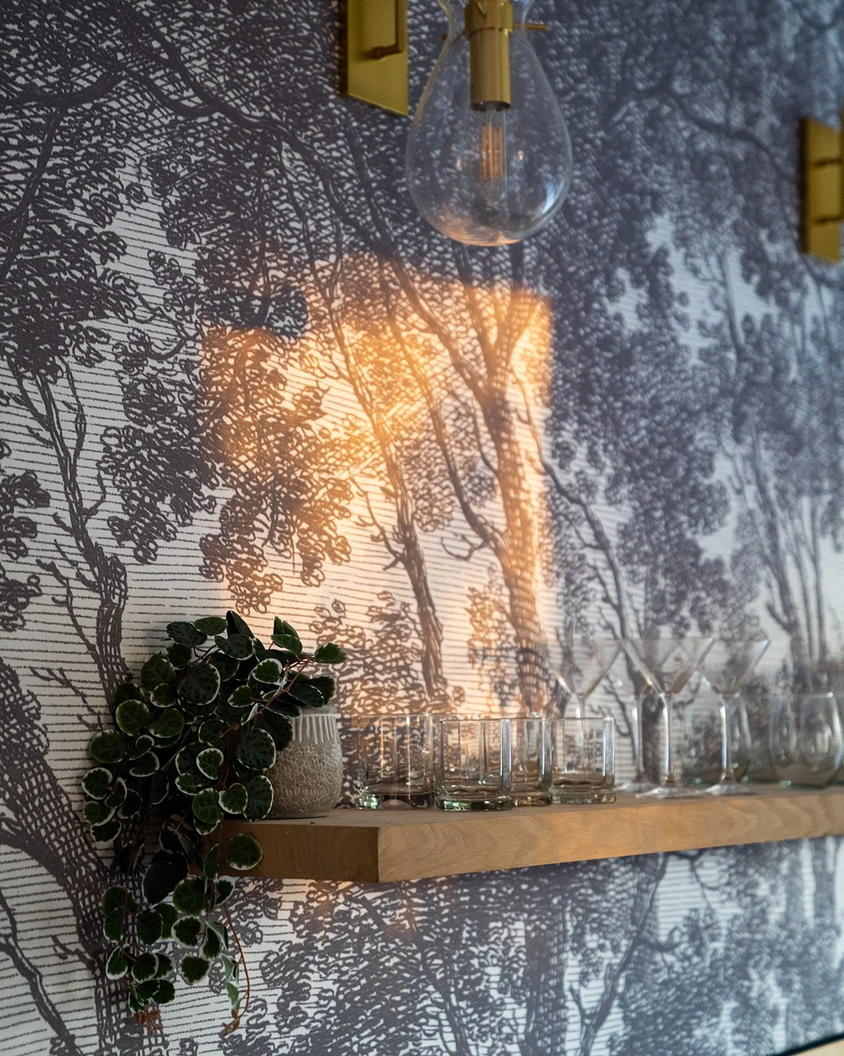 Wall shelf with vintage glassware and textured wallpaper.