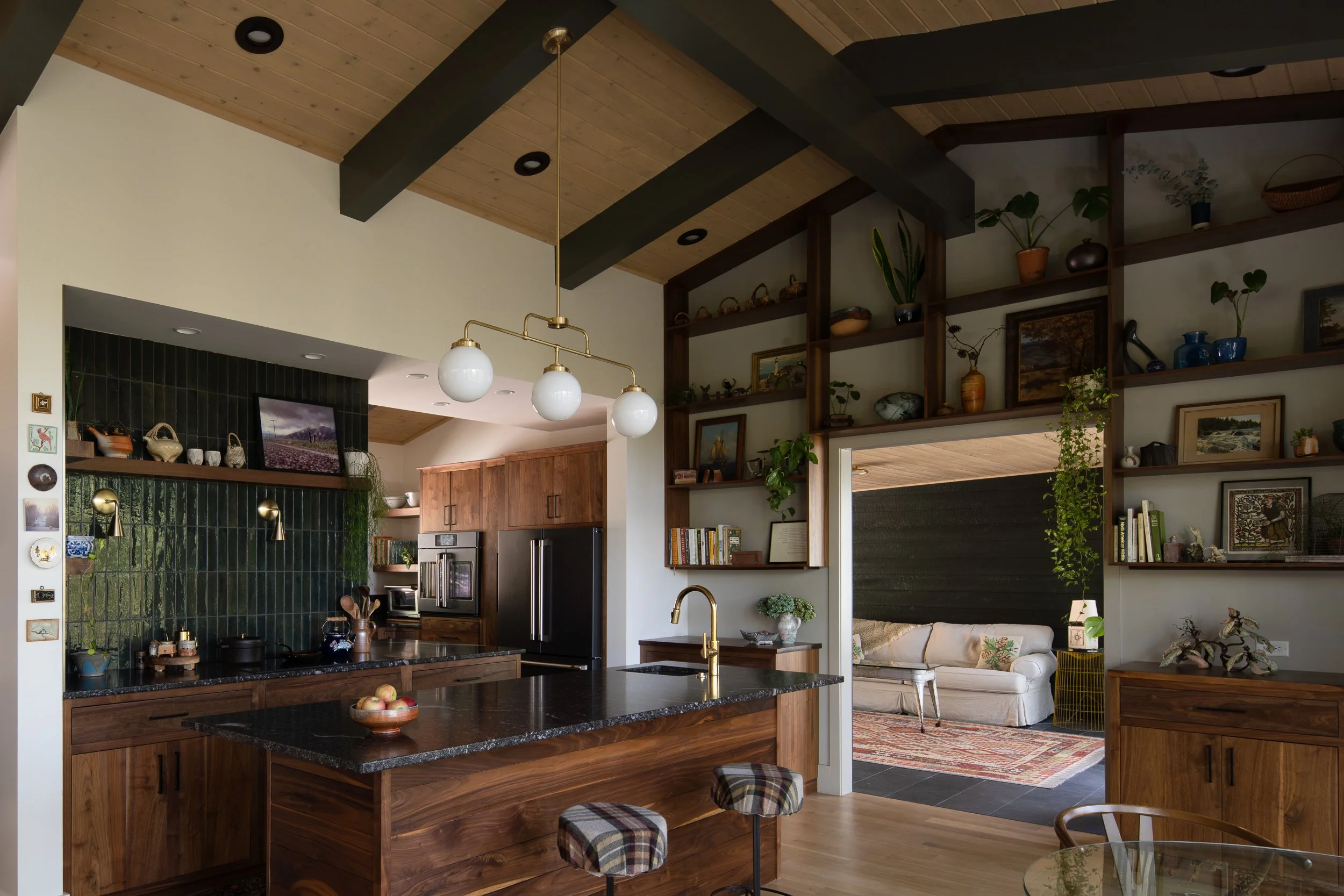 Walnut kitchen with dark countertops, green tile, open shelving, and a vaulted ceiling.