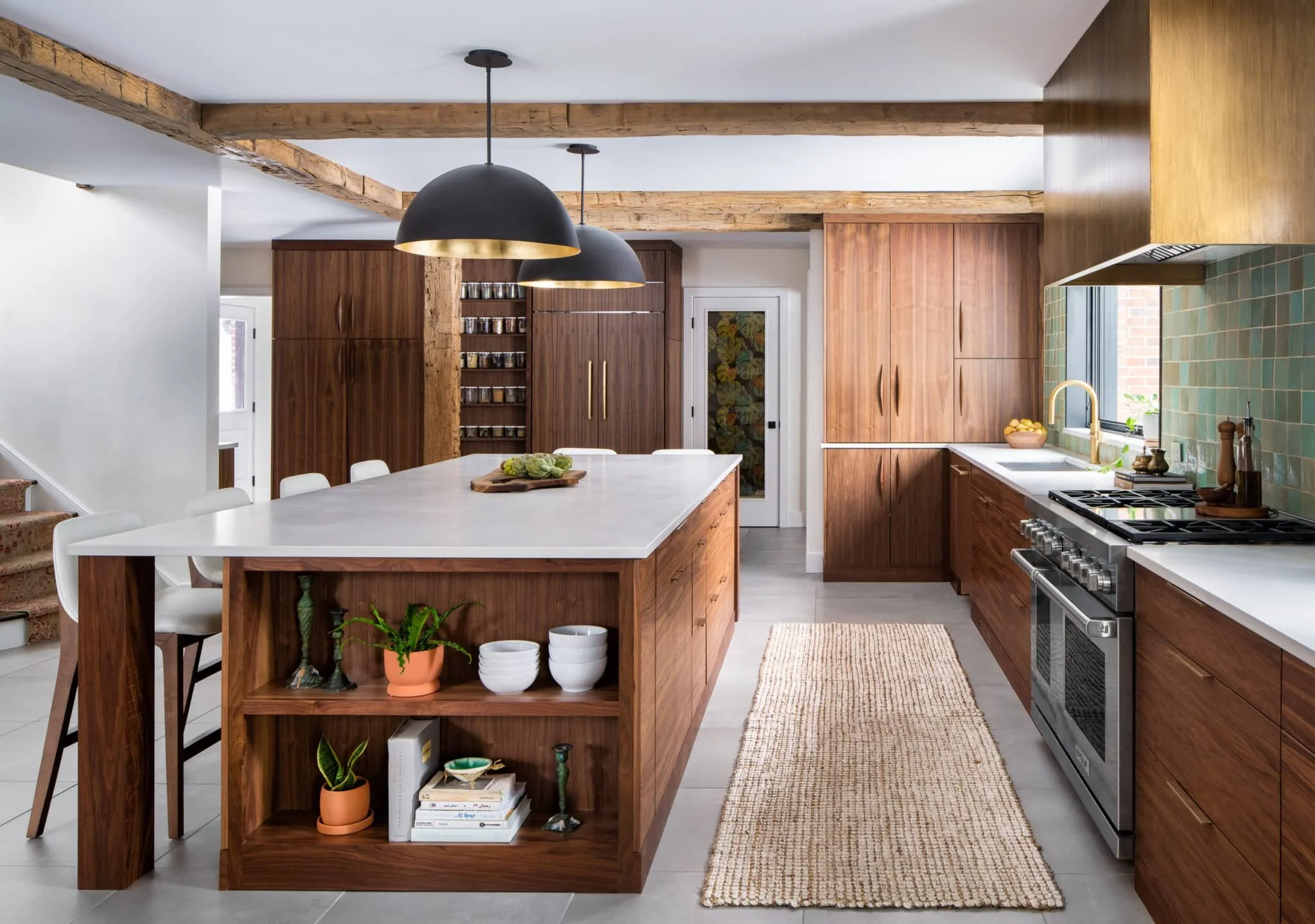 Bright kitchen with wood cabinetry, white island, exposed beams, and green tile backsplash.