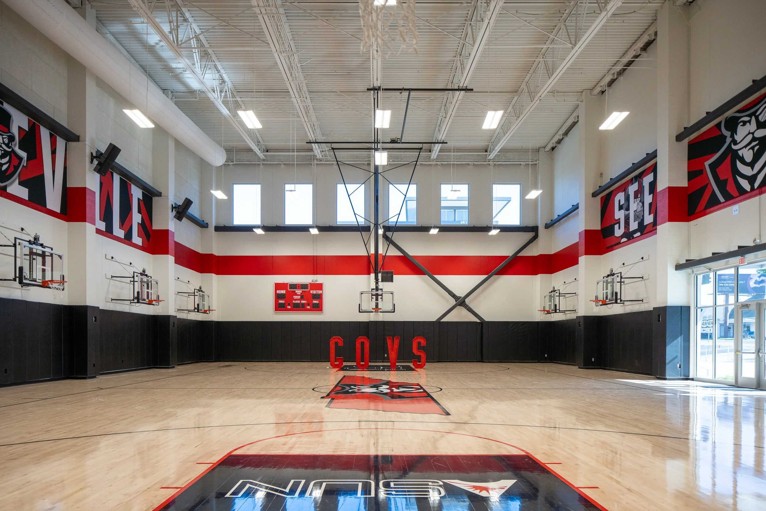 Spacious basketball court with polished wood floors and bold team graphics.