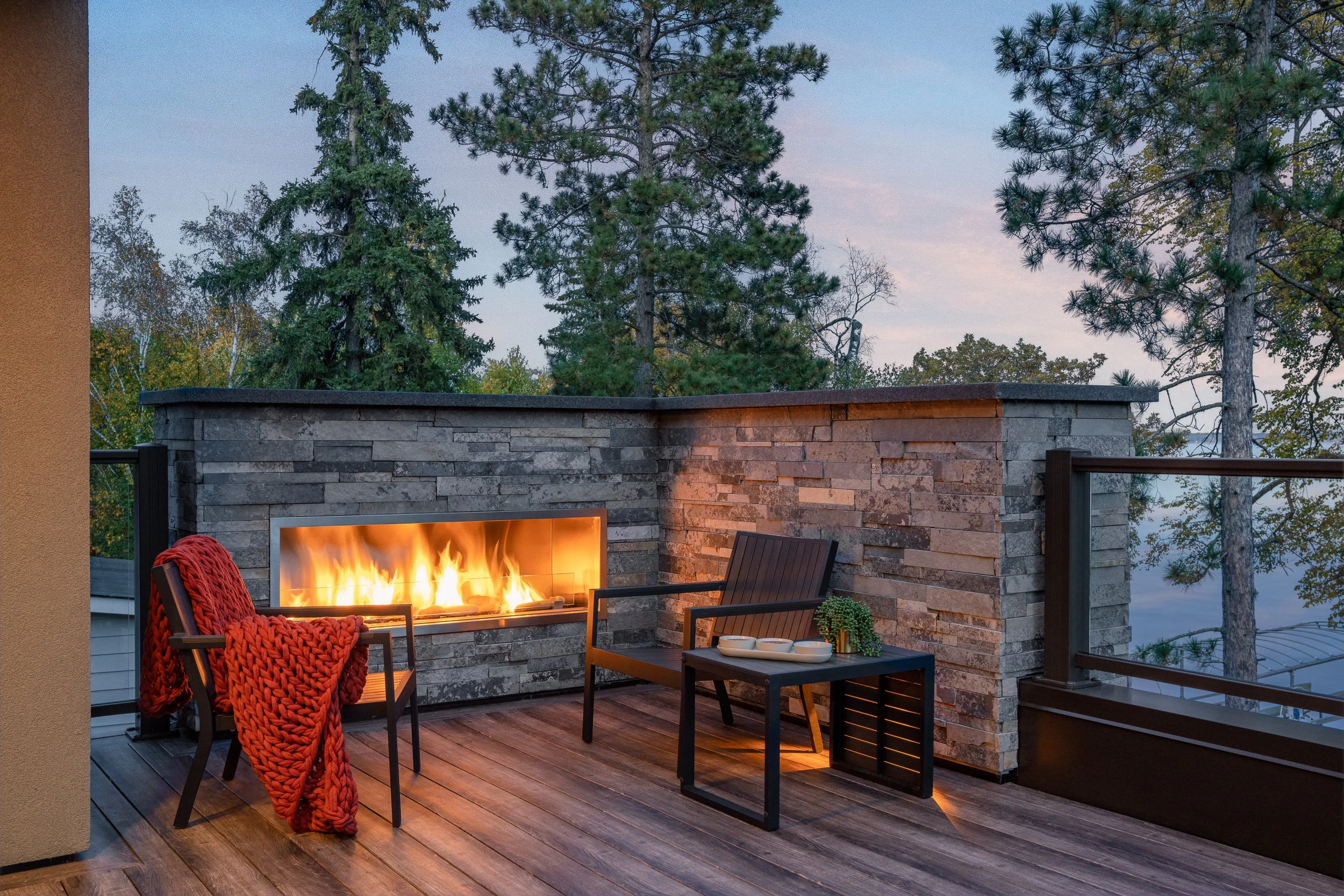 Rooftop patio with a built-in fireplace and seating area overlooking the trees.