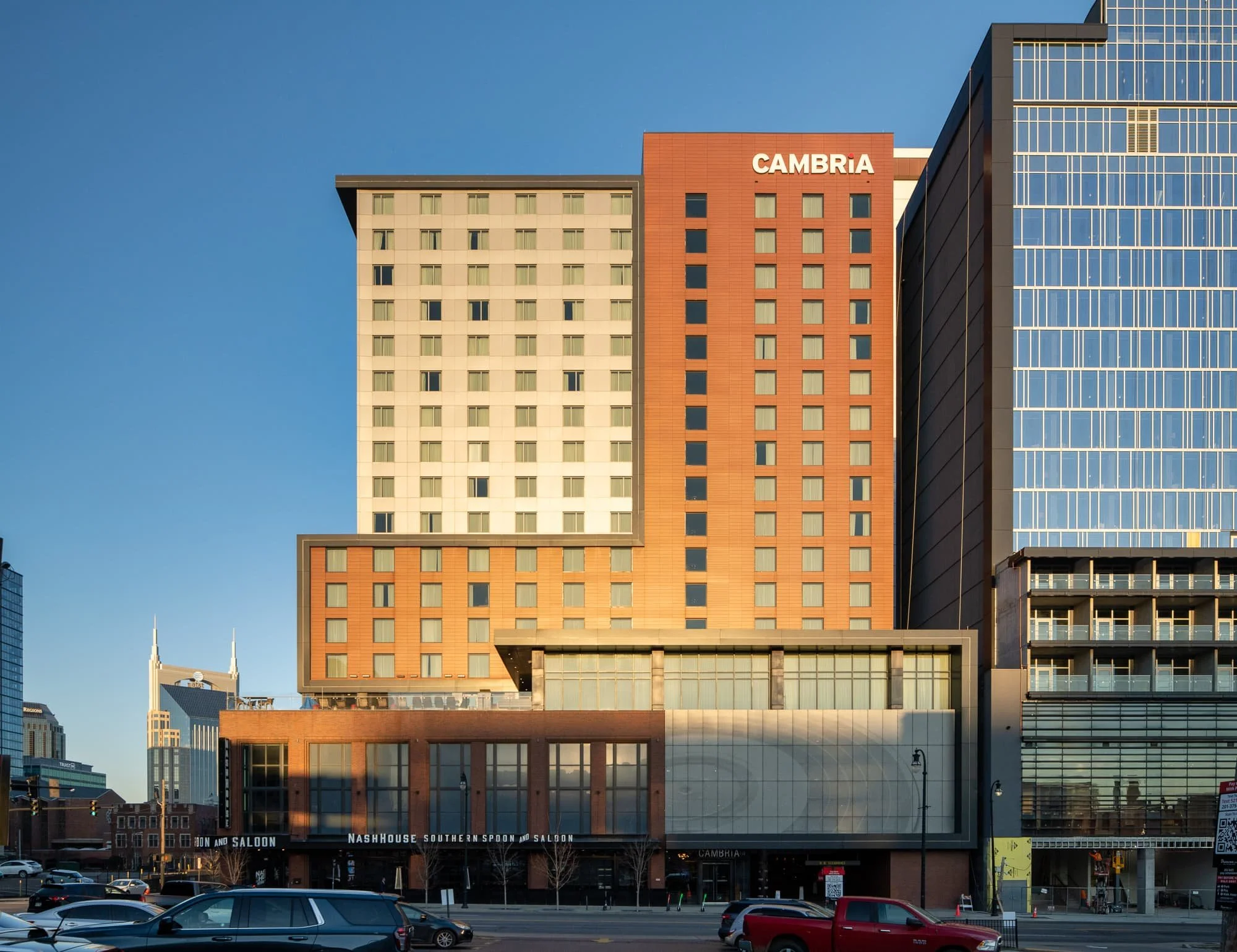 Cambria Hotel in downtown Nashville at 4:30pm with warm evening light raking across the red brick facade and softer ambient shadows