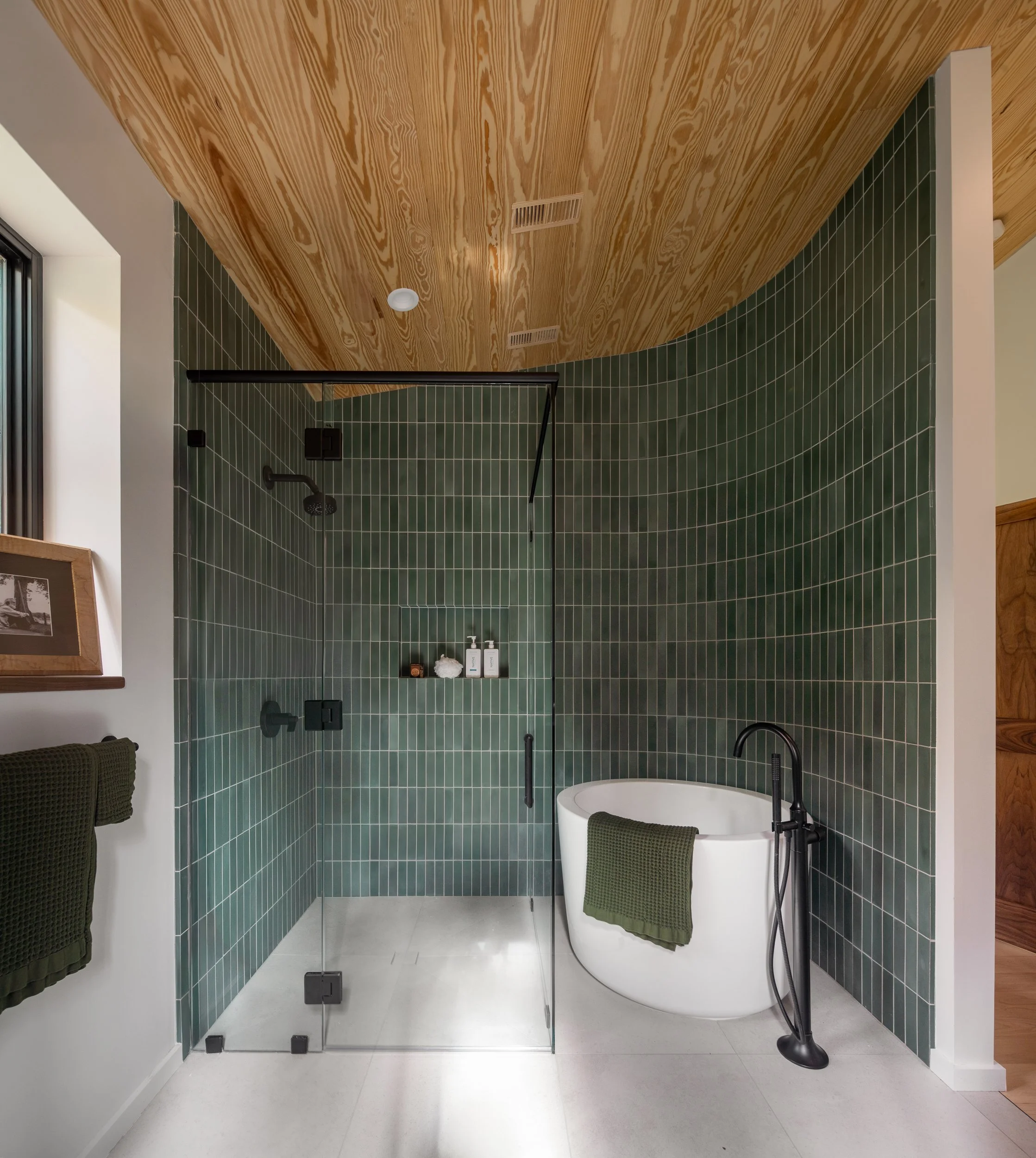 Open living, dining, and kitchen area with wood ceilings, large windows, and views into the autumn forest.
